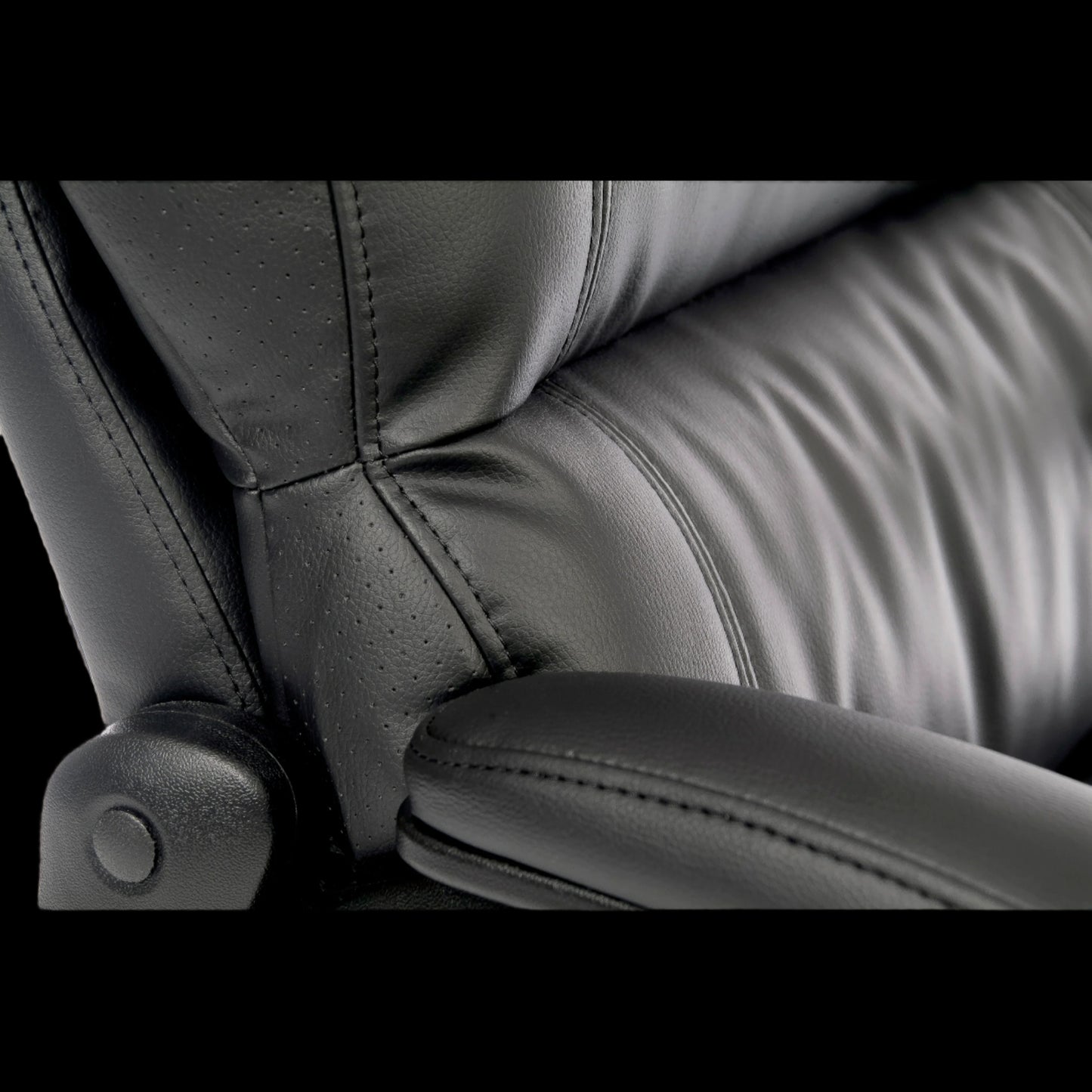 Close-up of a black leather office chair with visible stitching.
