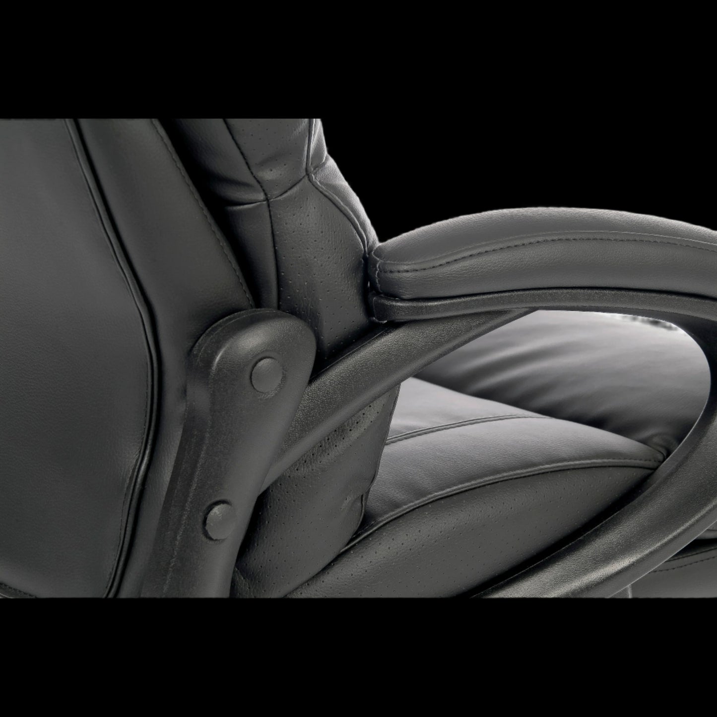 Close-up of a black office chair with armrests on a black background