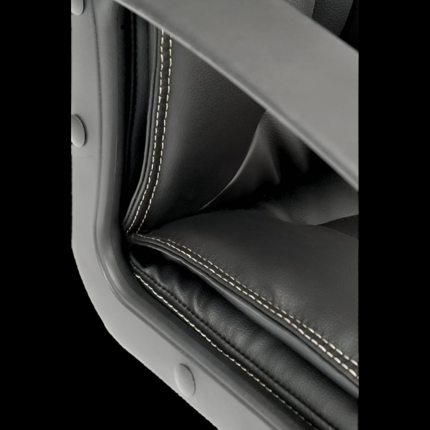 Close-up of a black leather seat with stitching detail on a black background