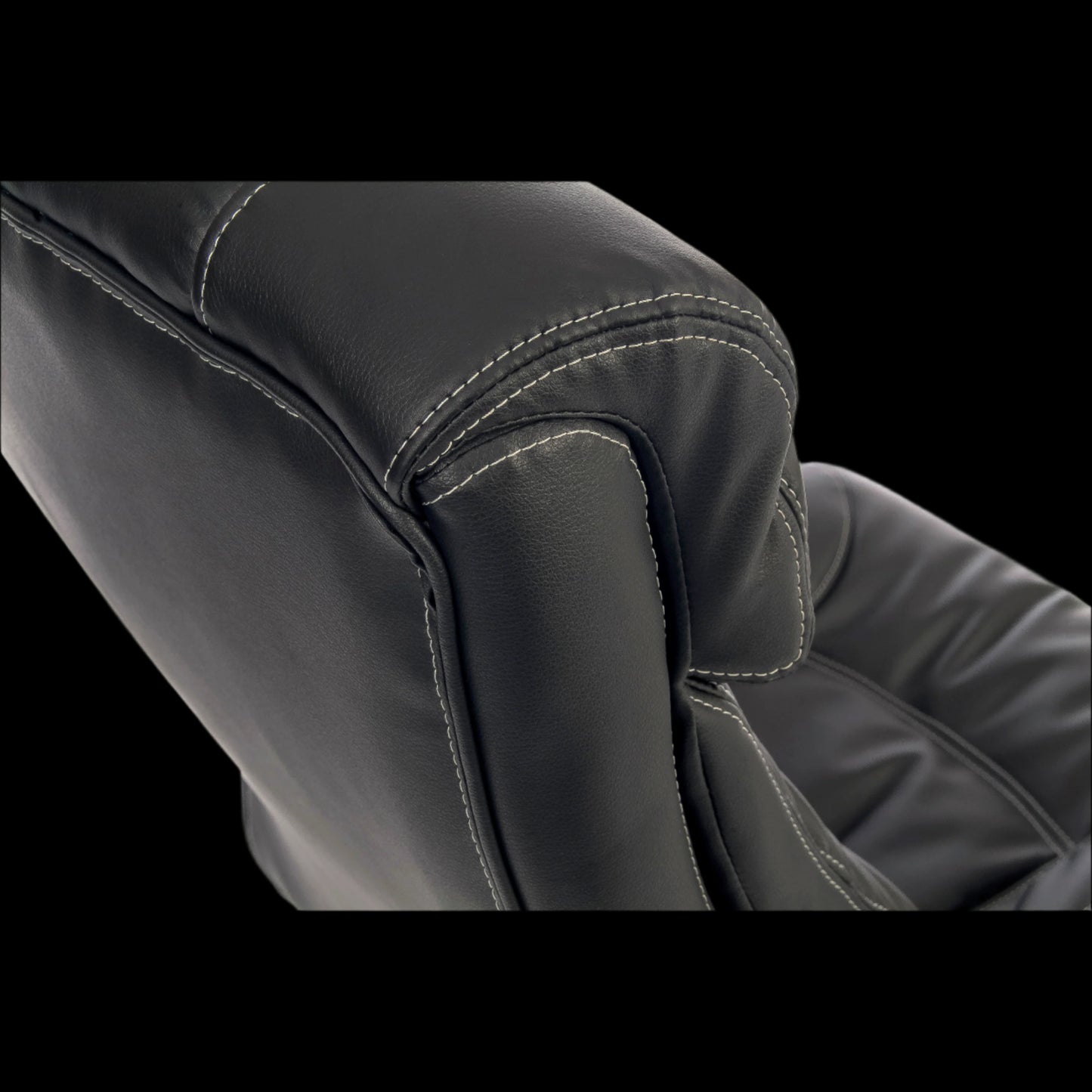Close-up of a black leather chair with visible stitching on a black background