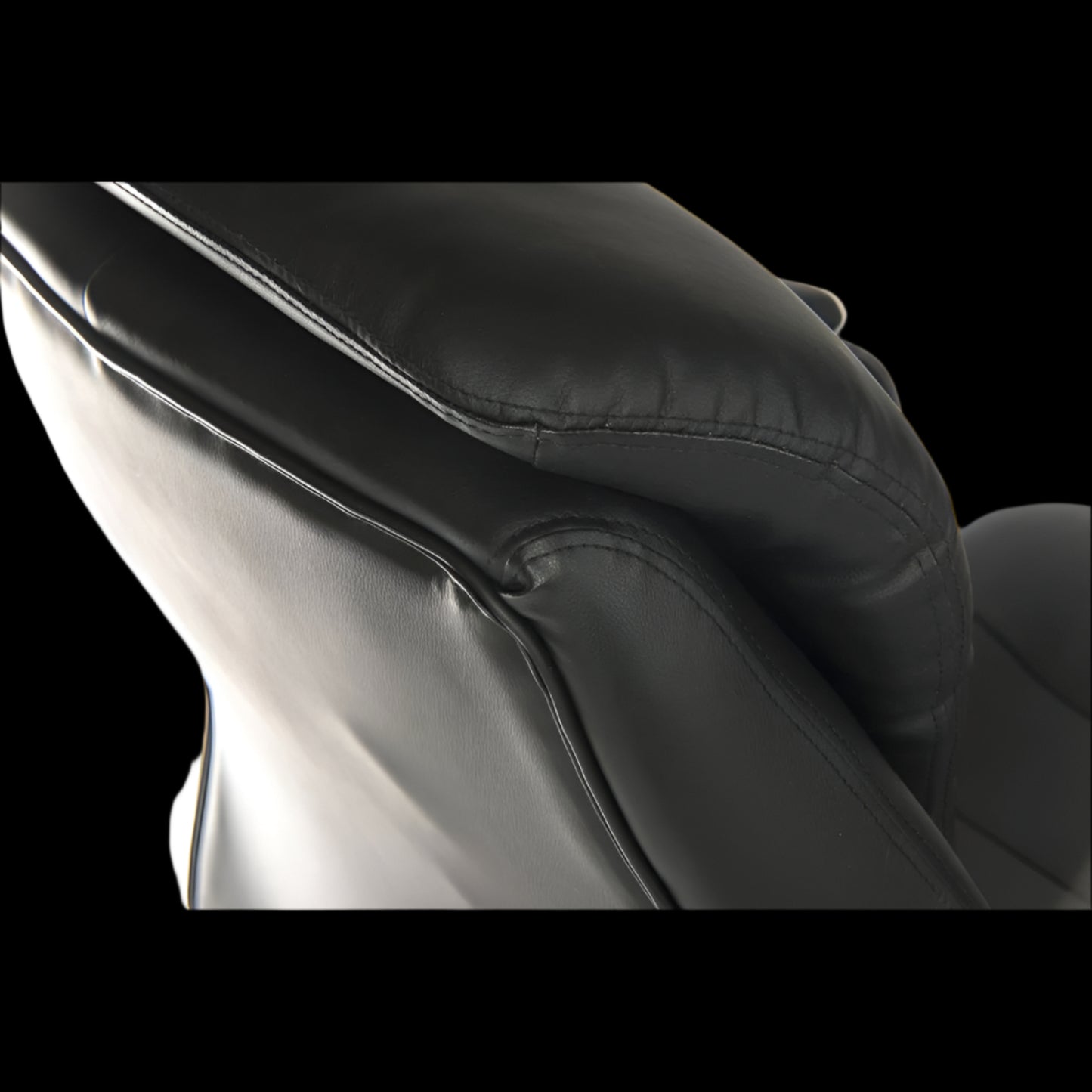 Close-up of a black leather seat with a thick interior on a black background