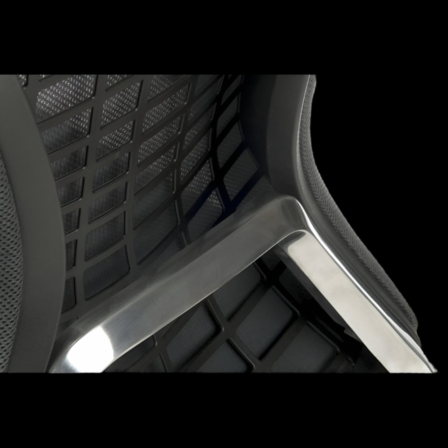 Close-up of a chair with mesh backrest and armrests on a black background