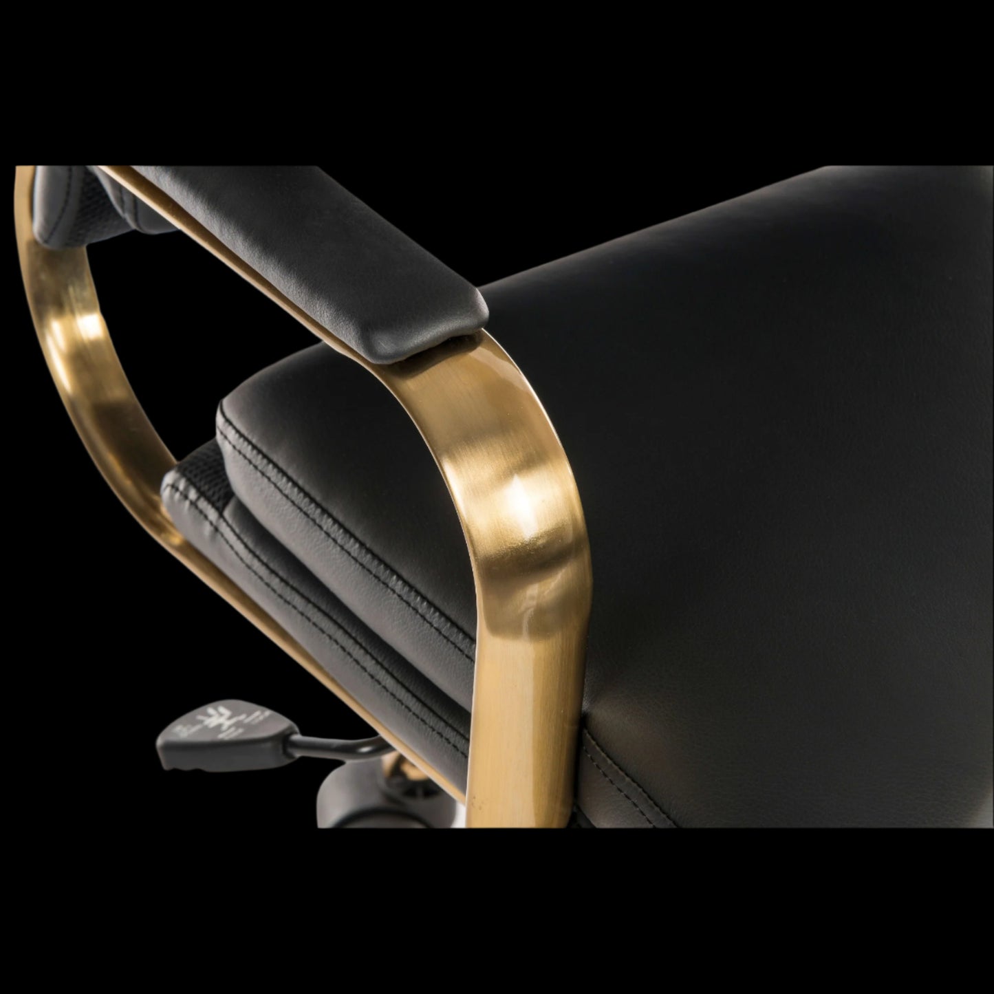 Close-up of a black leather chair with gold armrests on a black background