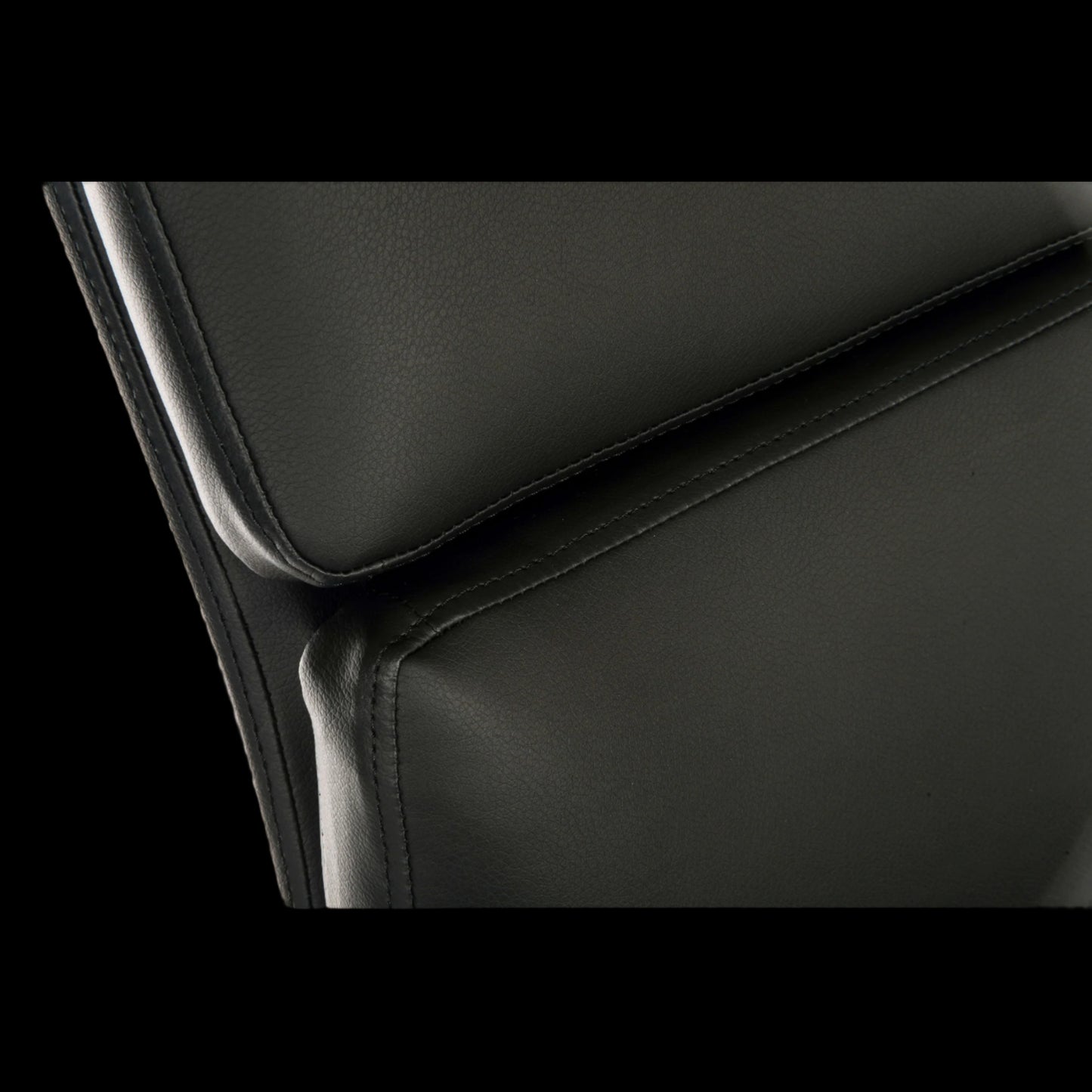 Close-up of a black leather chair with a focus on the seat and backrest.