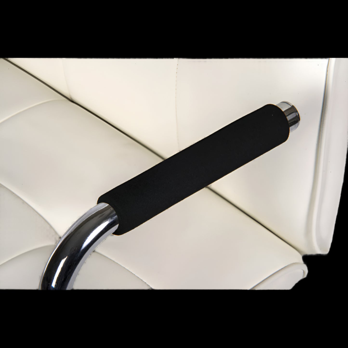 Close-up of a black handle with chrome finish on a white chair.