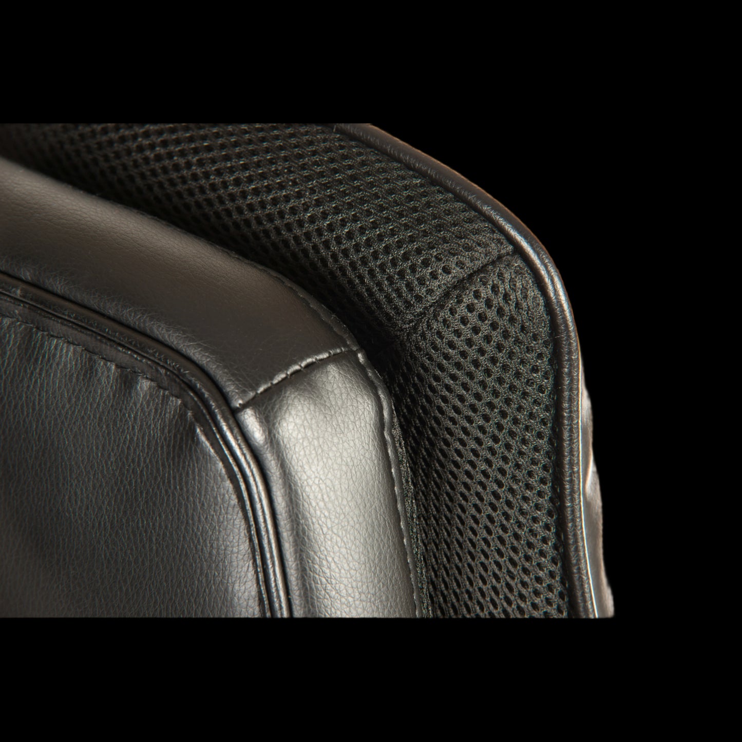 Close-up of a black leather and mesh chair backrest.