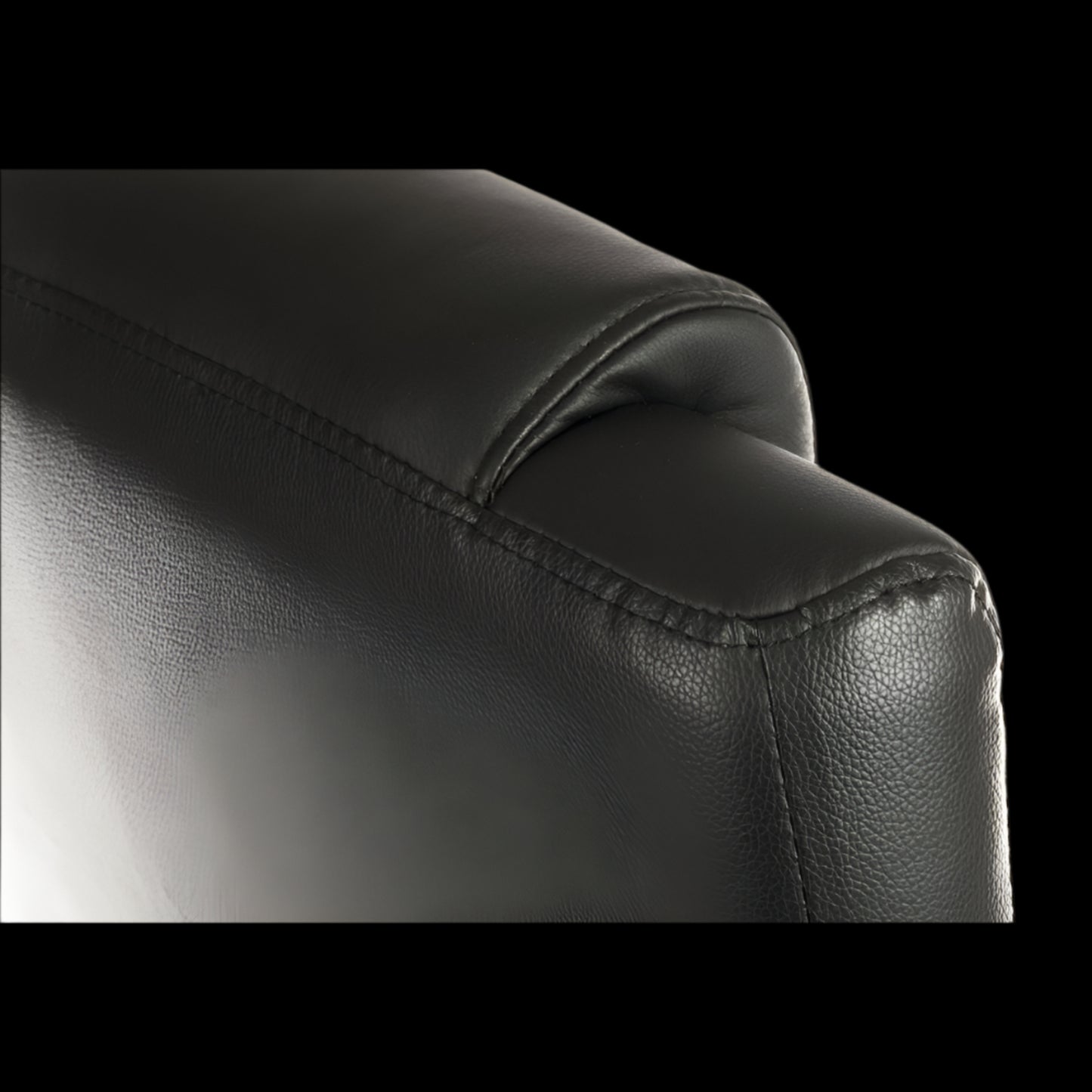 Close-up of a black leather armchair corner on a black background