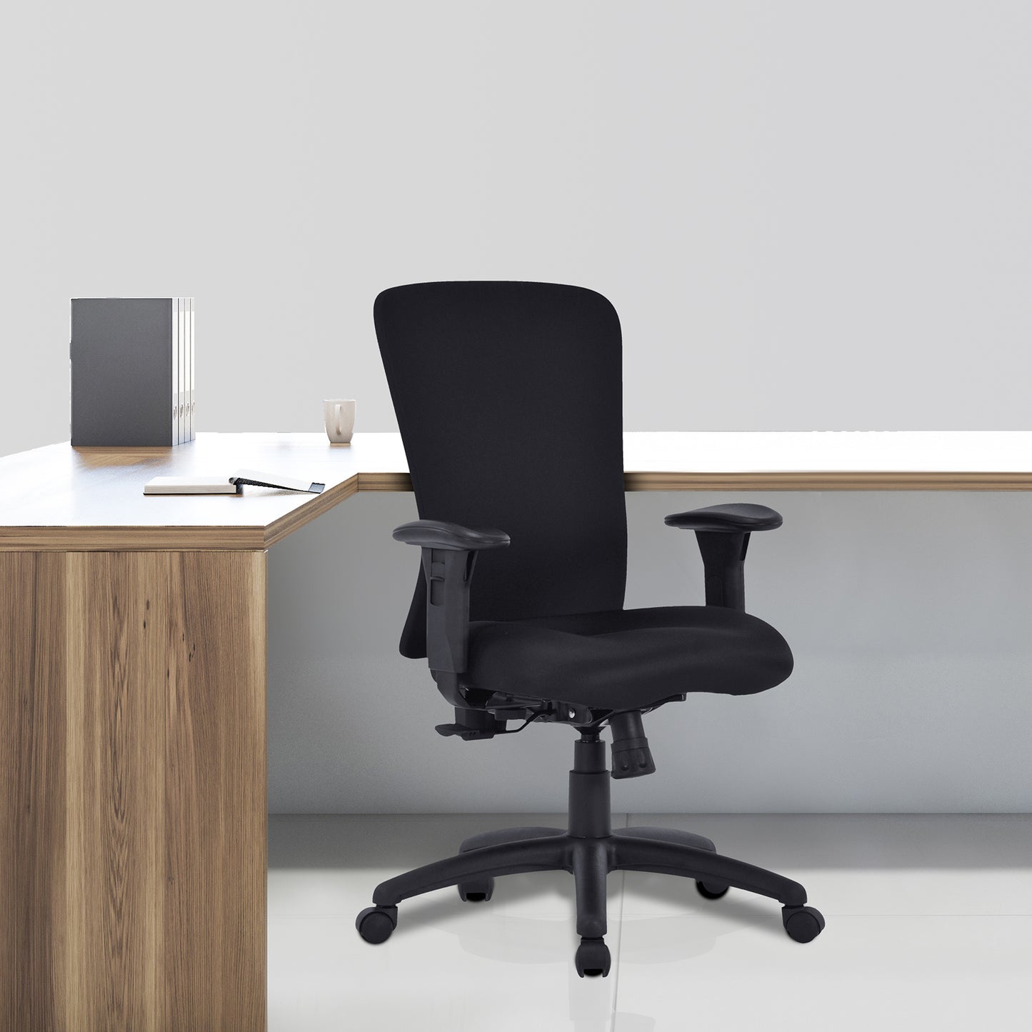 Black office chair in front of a wooden desk with a white surface.