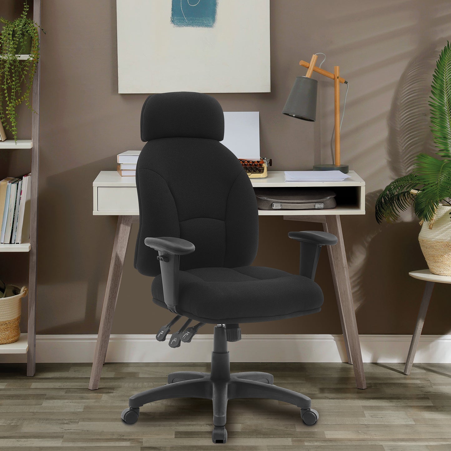 Black office chair in front of a white desk with a lamp and books in a room setting.