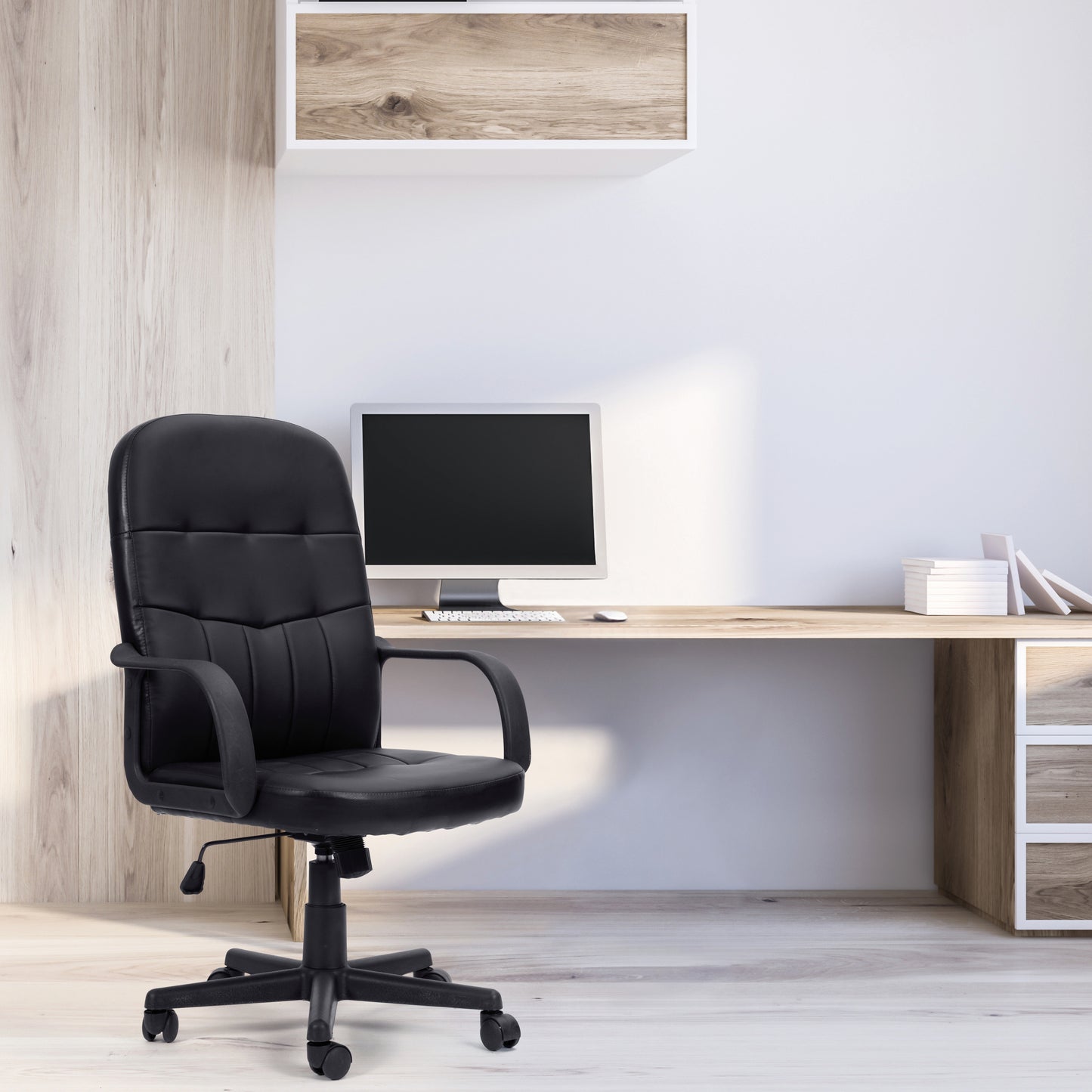 Black office chair in front of a wooden desk with a computer setup.