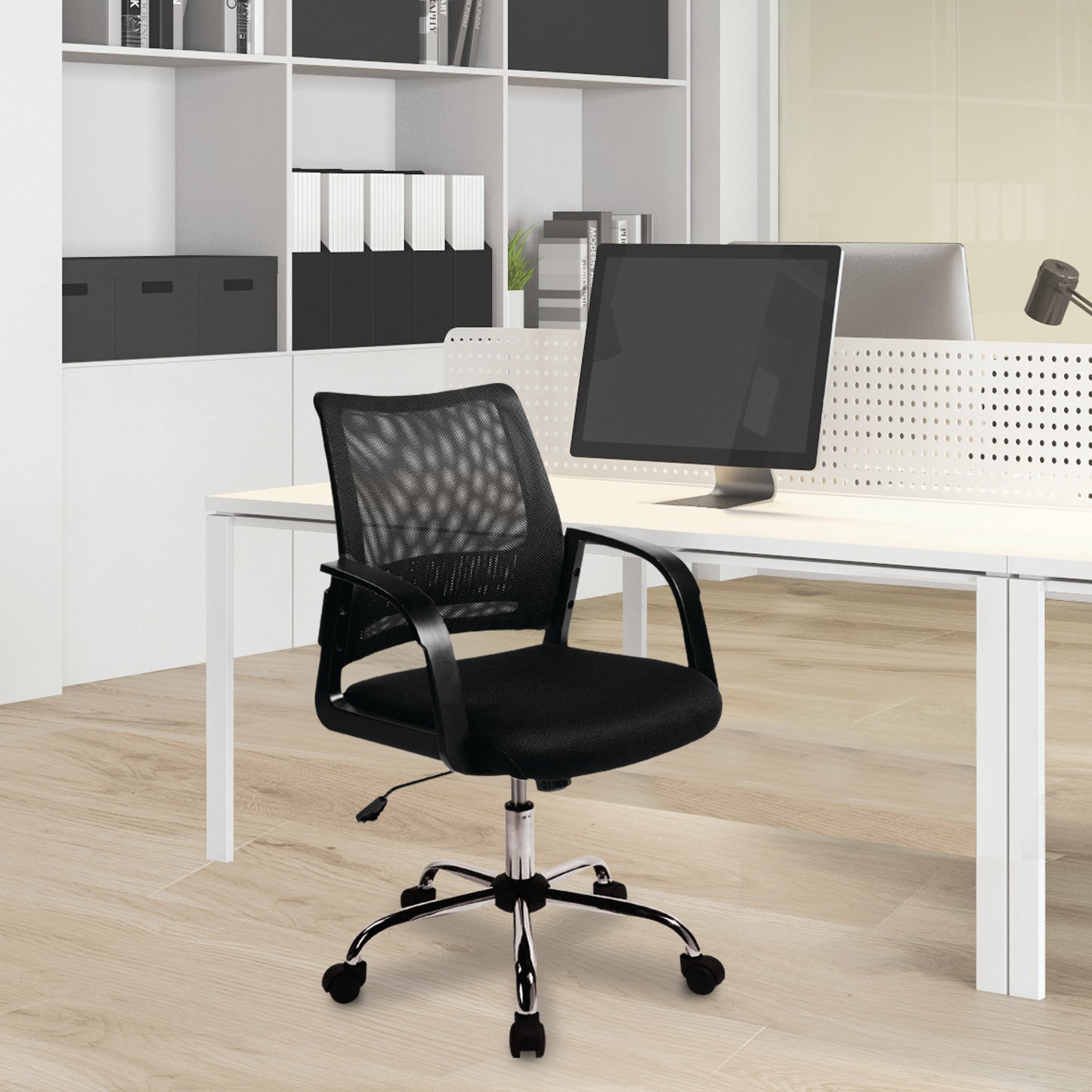 Black office chair in front of a white desk with a computer monitor in an office setting.