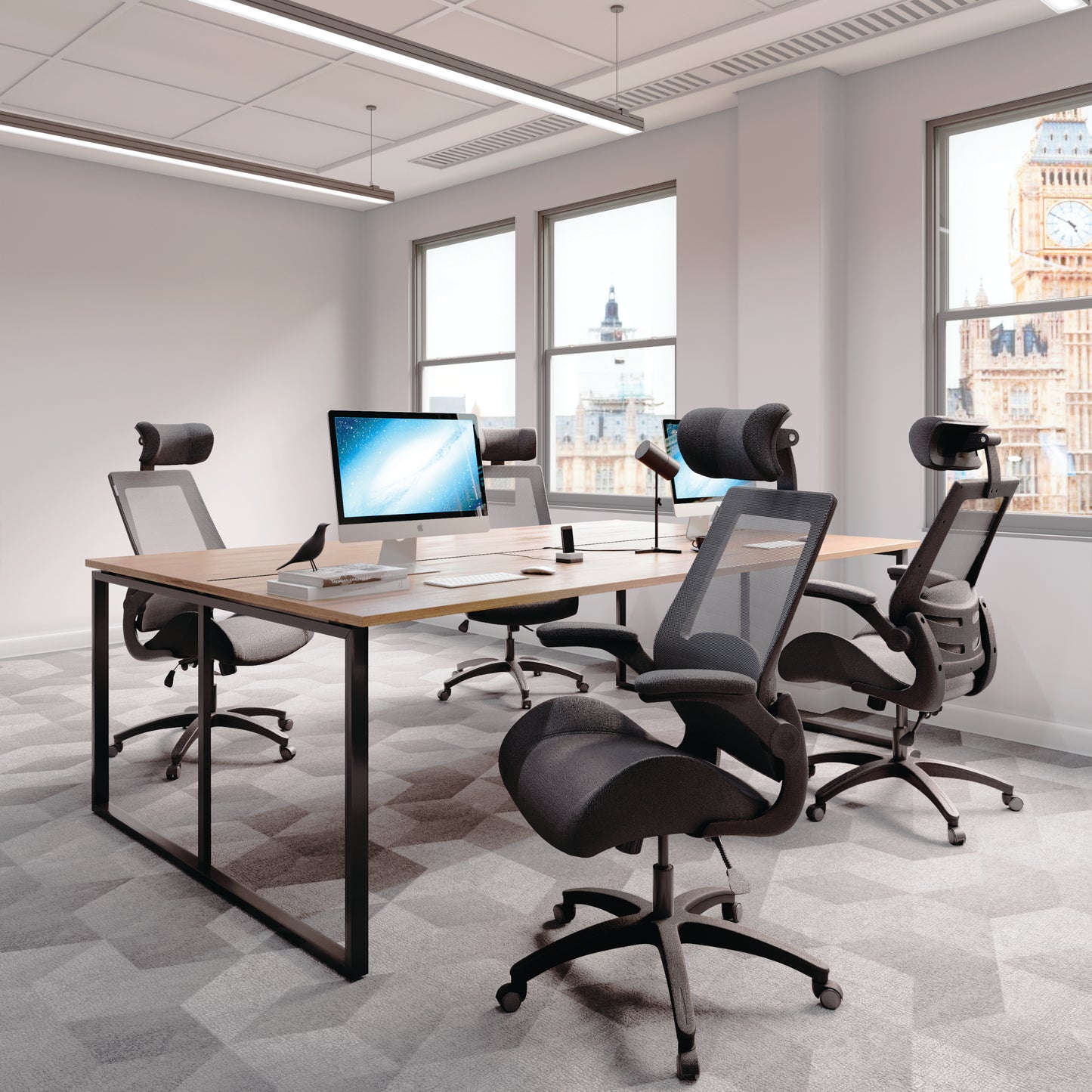 Modern office setup with desks, chairs, and computer monitors in a bright room.
