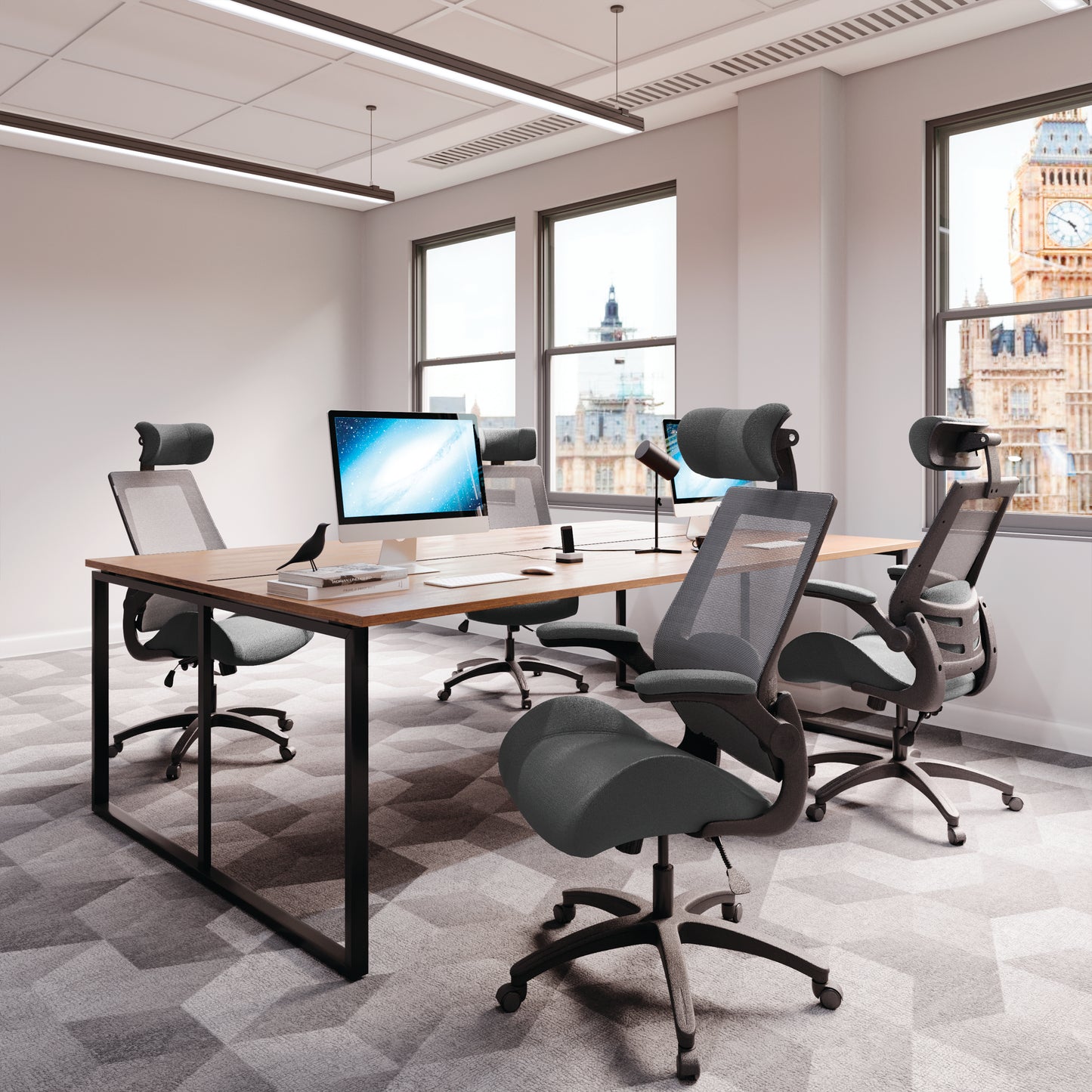 Modern office setup with desks, chairs, and computer monitors in a bright room.