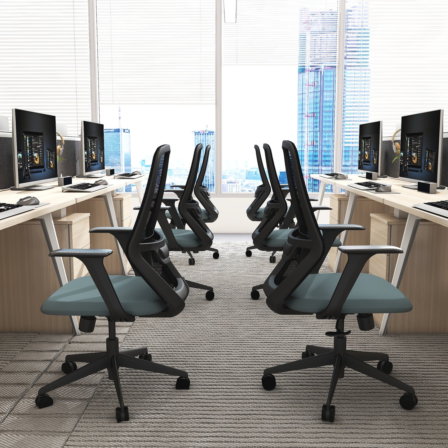 Modern office setup with desks, chairs, and computer monitors in a bright room.