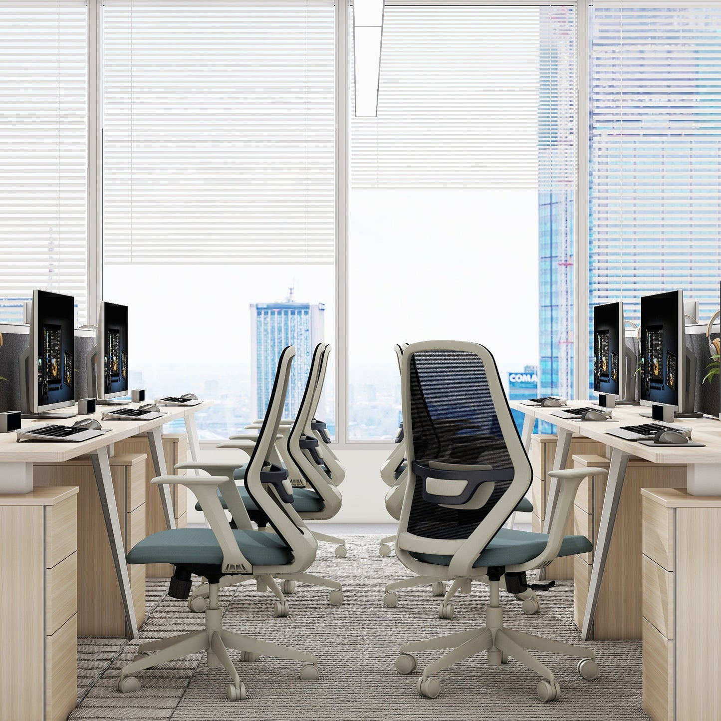 Modern office setup with ergonomic chairs and computer monitors in a bright room with large windows.