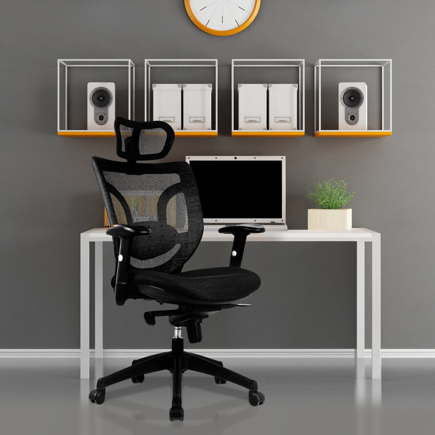 Black office chair in front of a white desk with a computer setup against a gray wall.