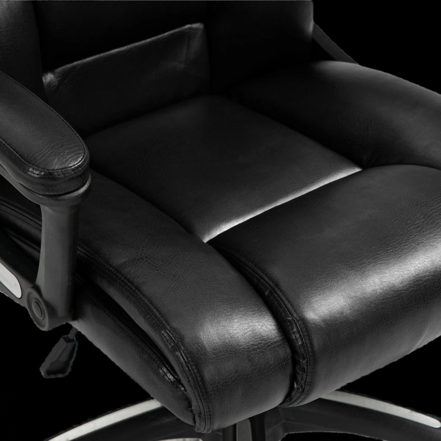 Close-up of a black office chair with leather seat and armrests on a black background
