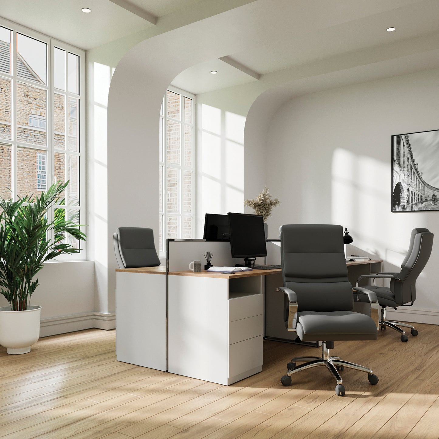 Modern office setup with desks, chairs, and large windows.