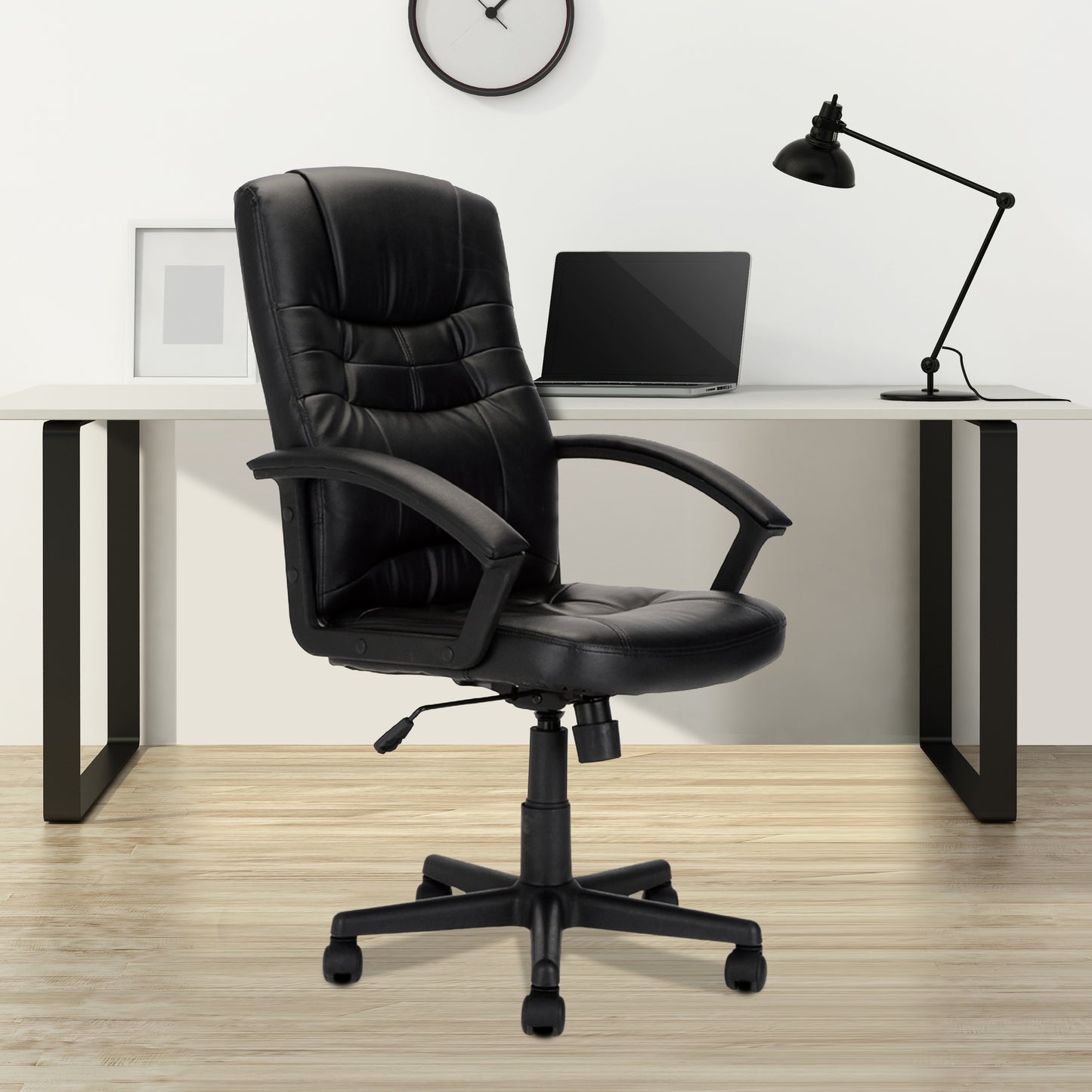Black office chair in front of a desk with a laptop and lamp.