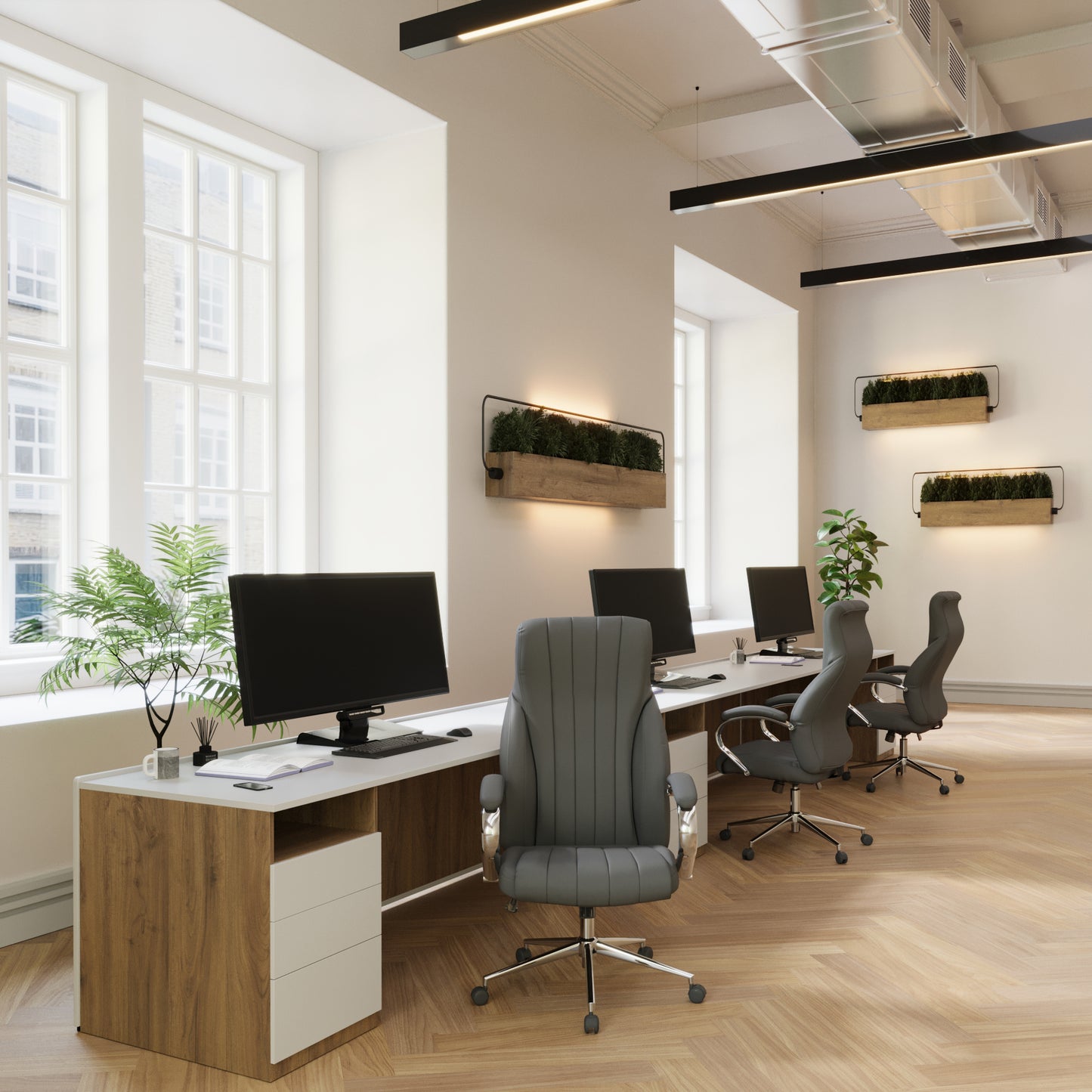 Modern office setup with desks, chairs, and computer monitors in a bright room.