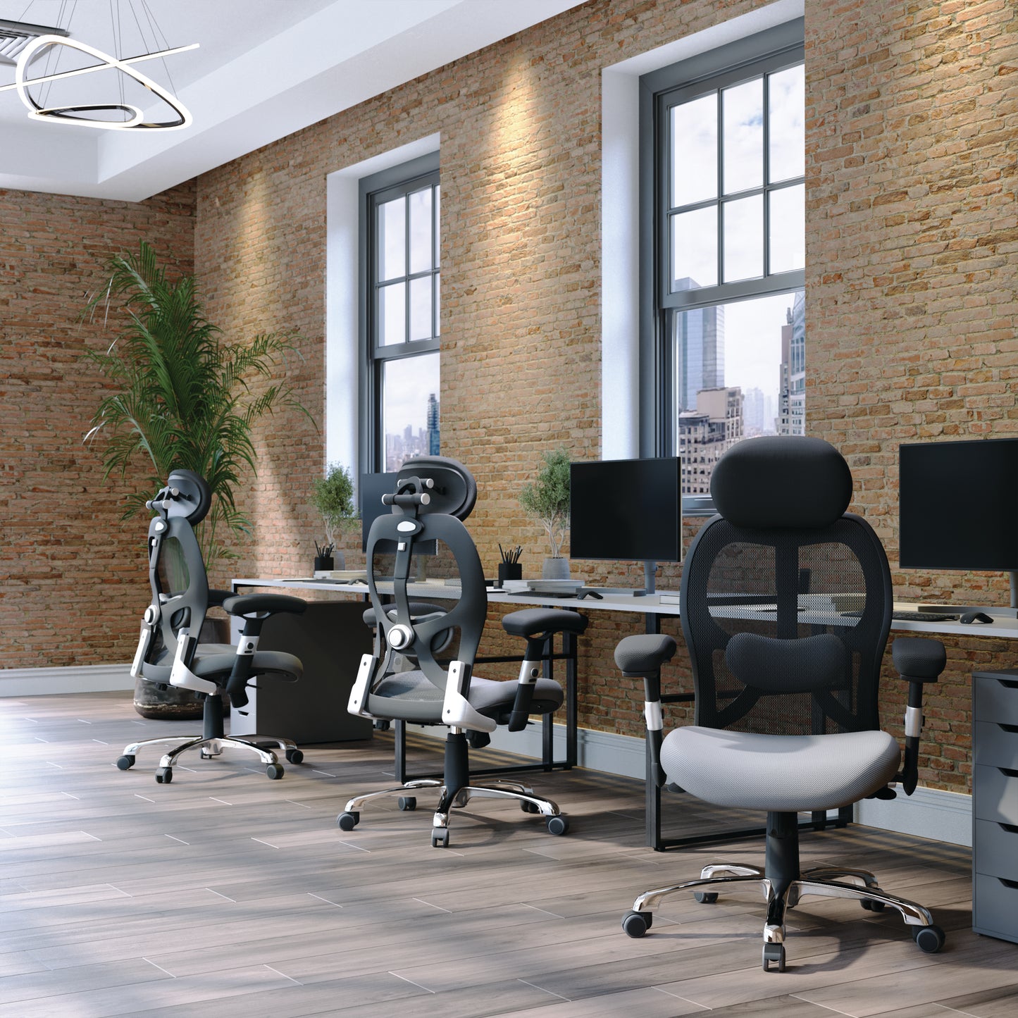 Modern office setup with ergonomic chairs and desks against a brick wall.