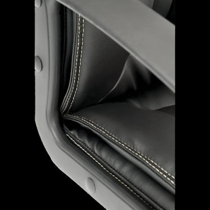 Close-up of a black leather seat with stitching detail on a black background