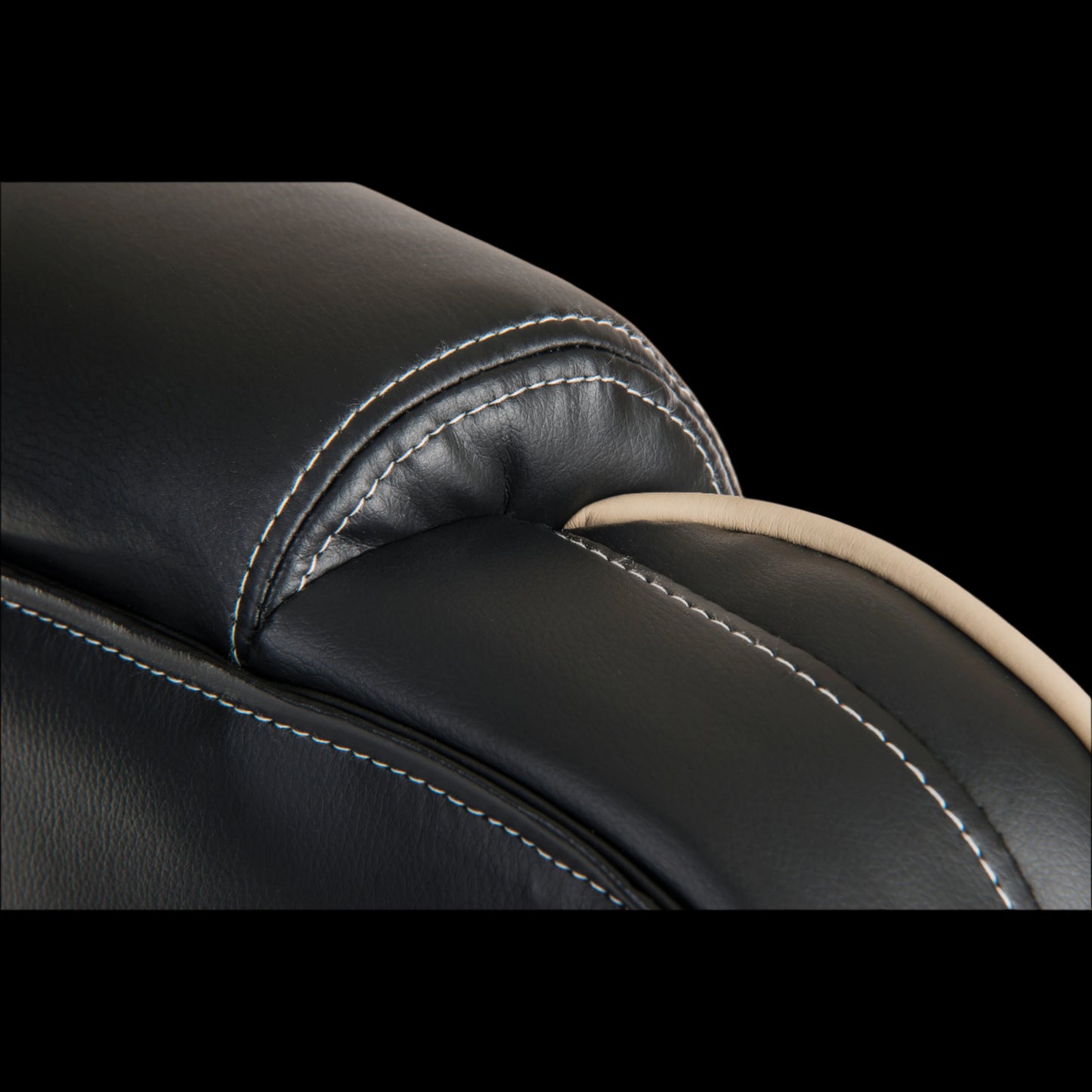 Close-up of a black leather seat with stitching detail on a black background