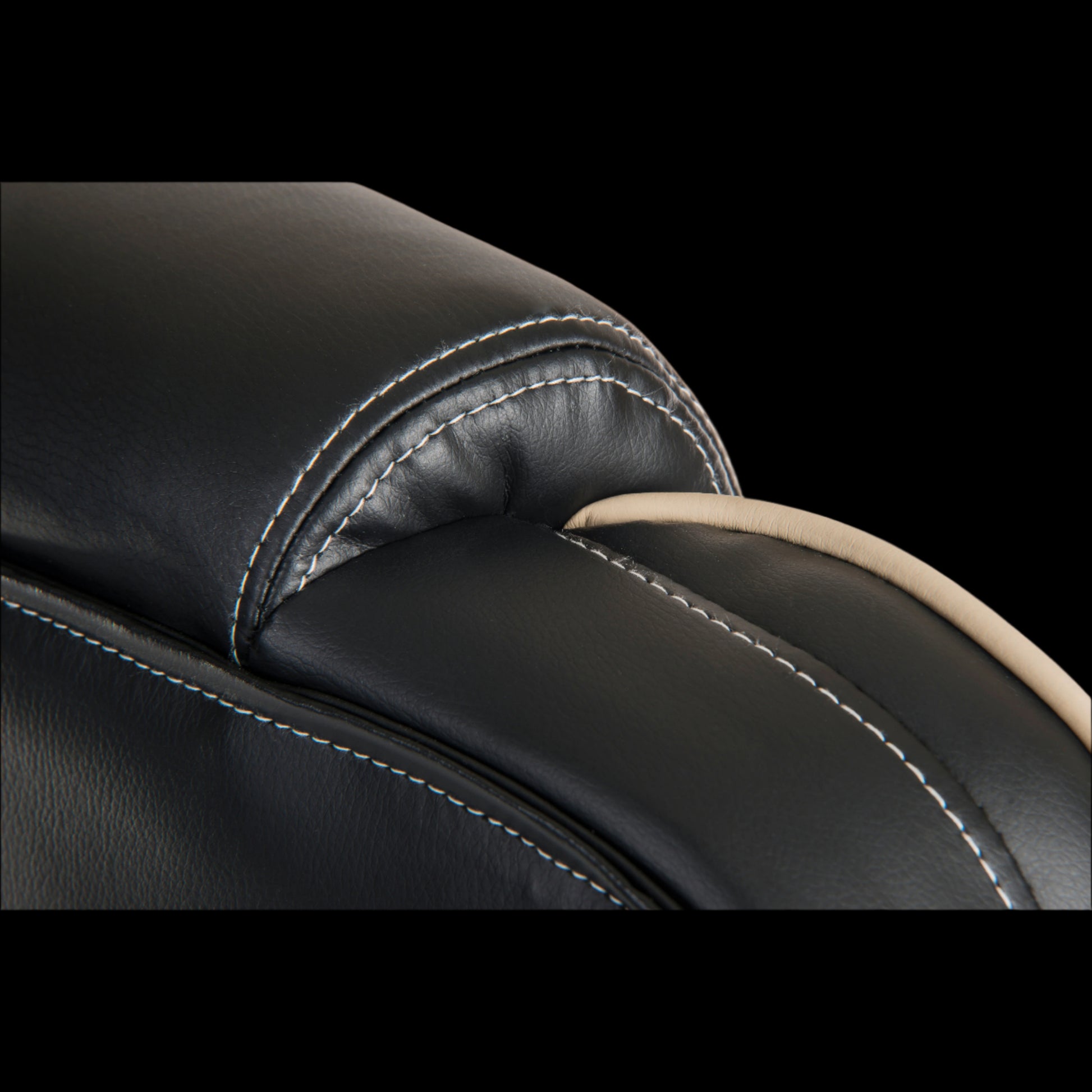 Close-up of a black leather seat with stitching detail on a black background