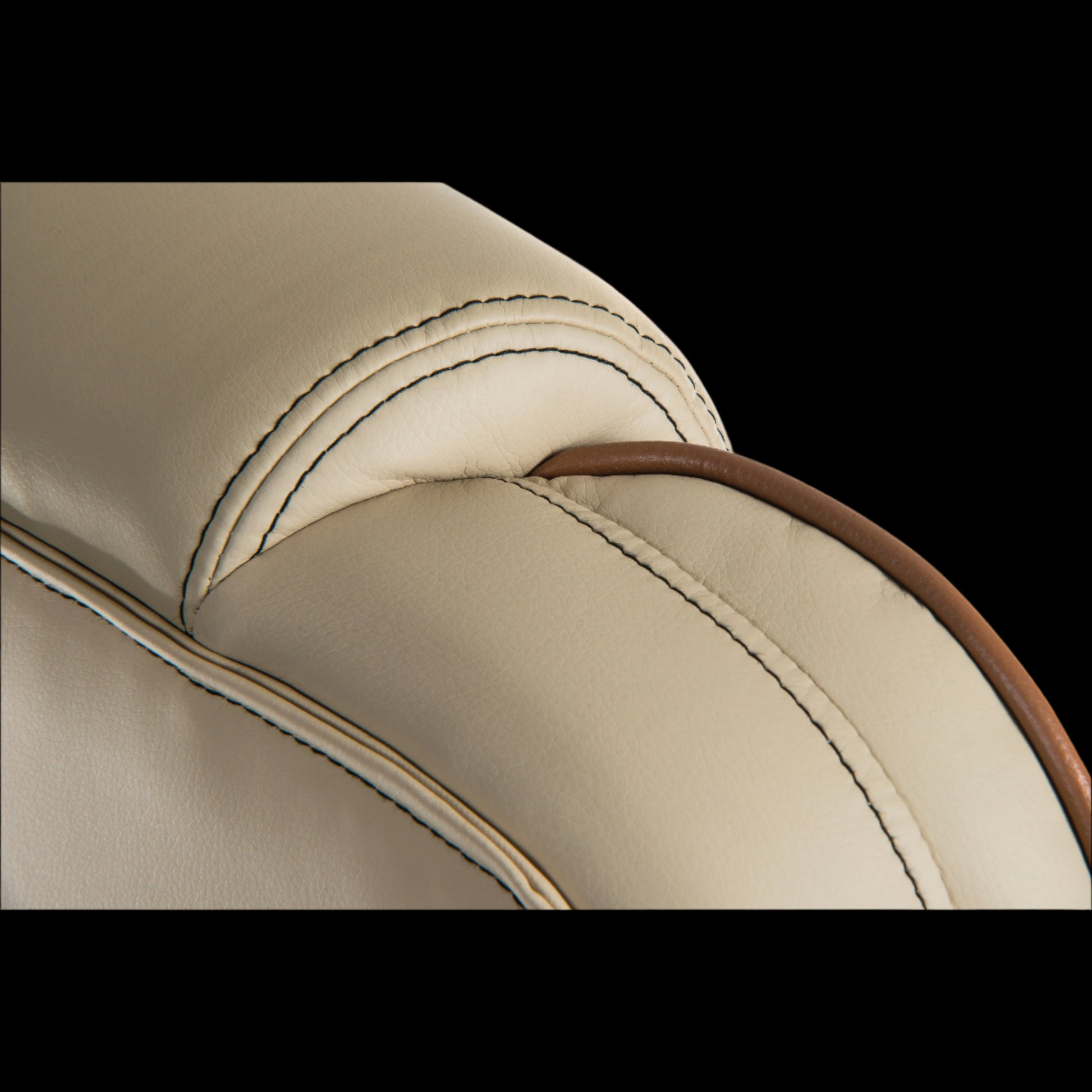 Close-up of a beige leather saddle with brown stitching on a black background