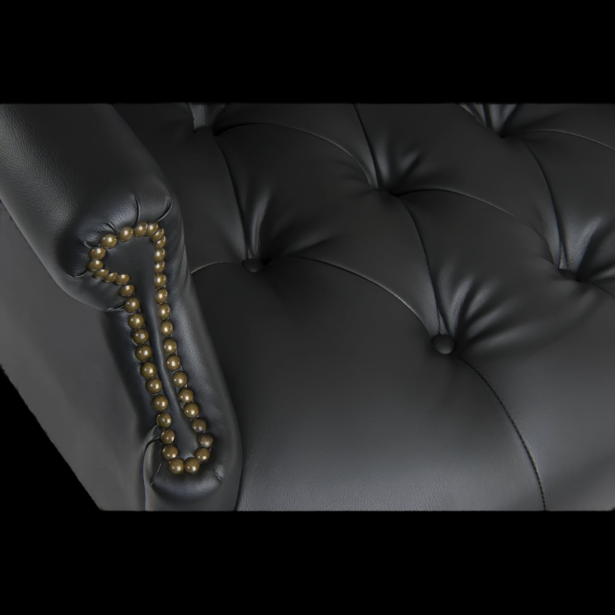 Close-up of a black leather armchair with tufted backrest and decorative armrest.