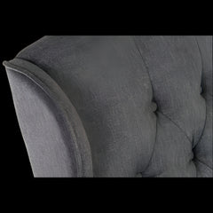 Gray upholstered chair with tufted backrest and armrests on a black background