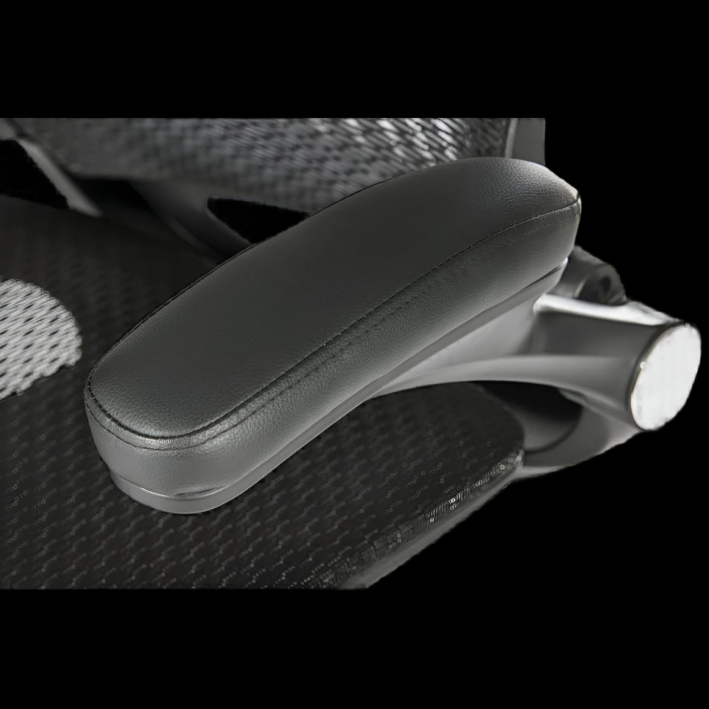 Close-up of a black office chair armrest with a textured backrest.