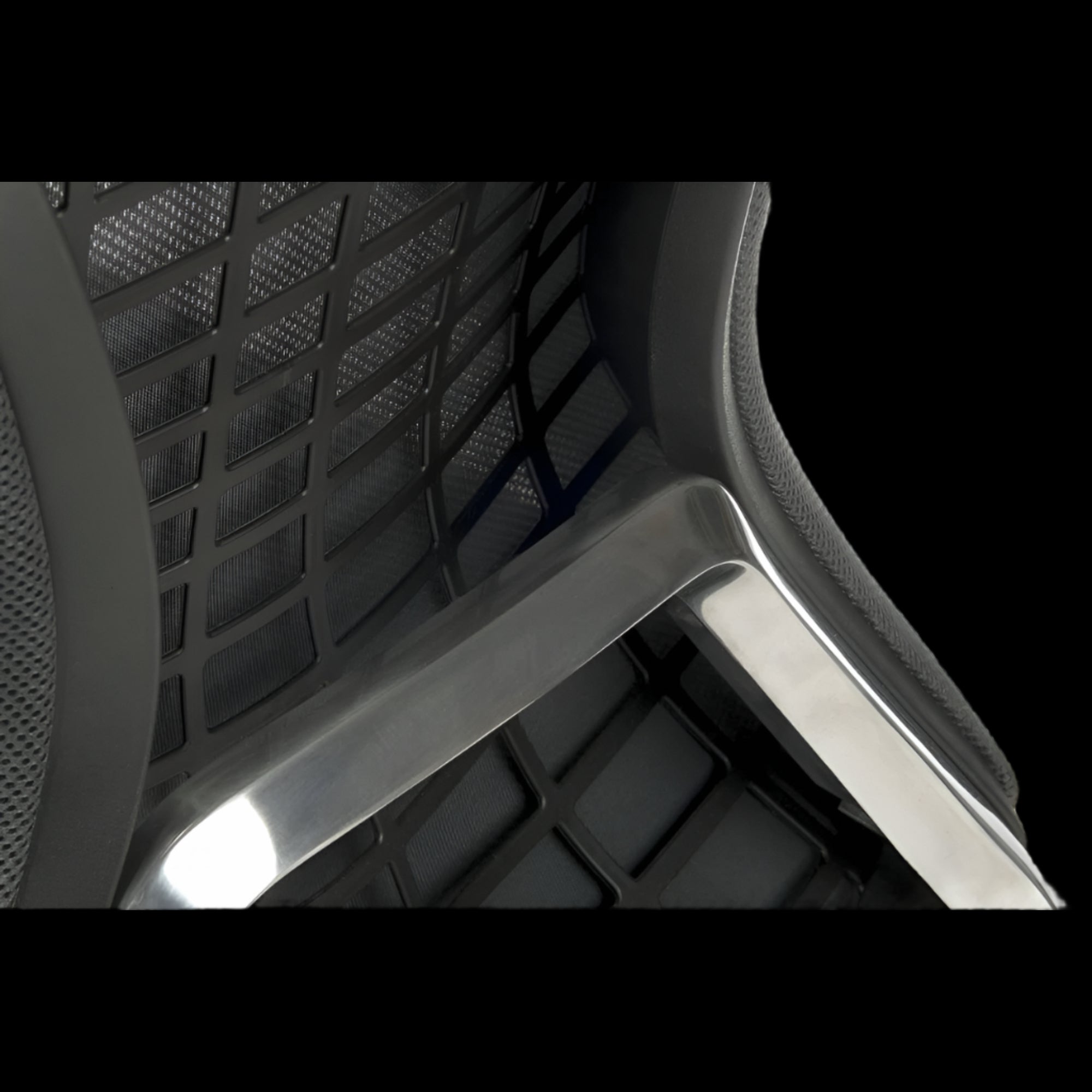 Close-up of a chair with mesh backrest and armrests on a black background