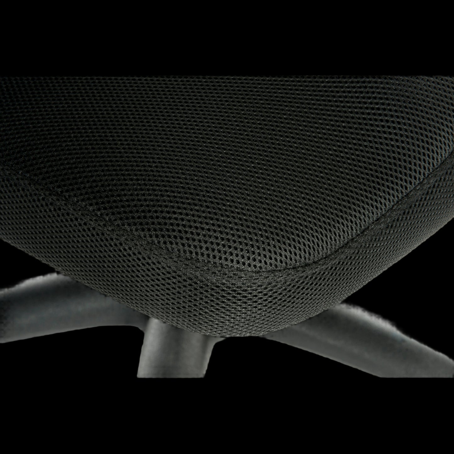 Close-up of a black office chair with mesh backrest on a black background