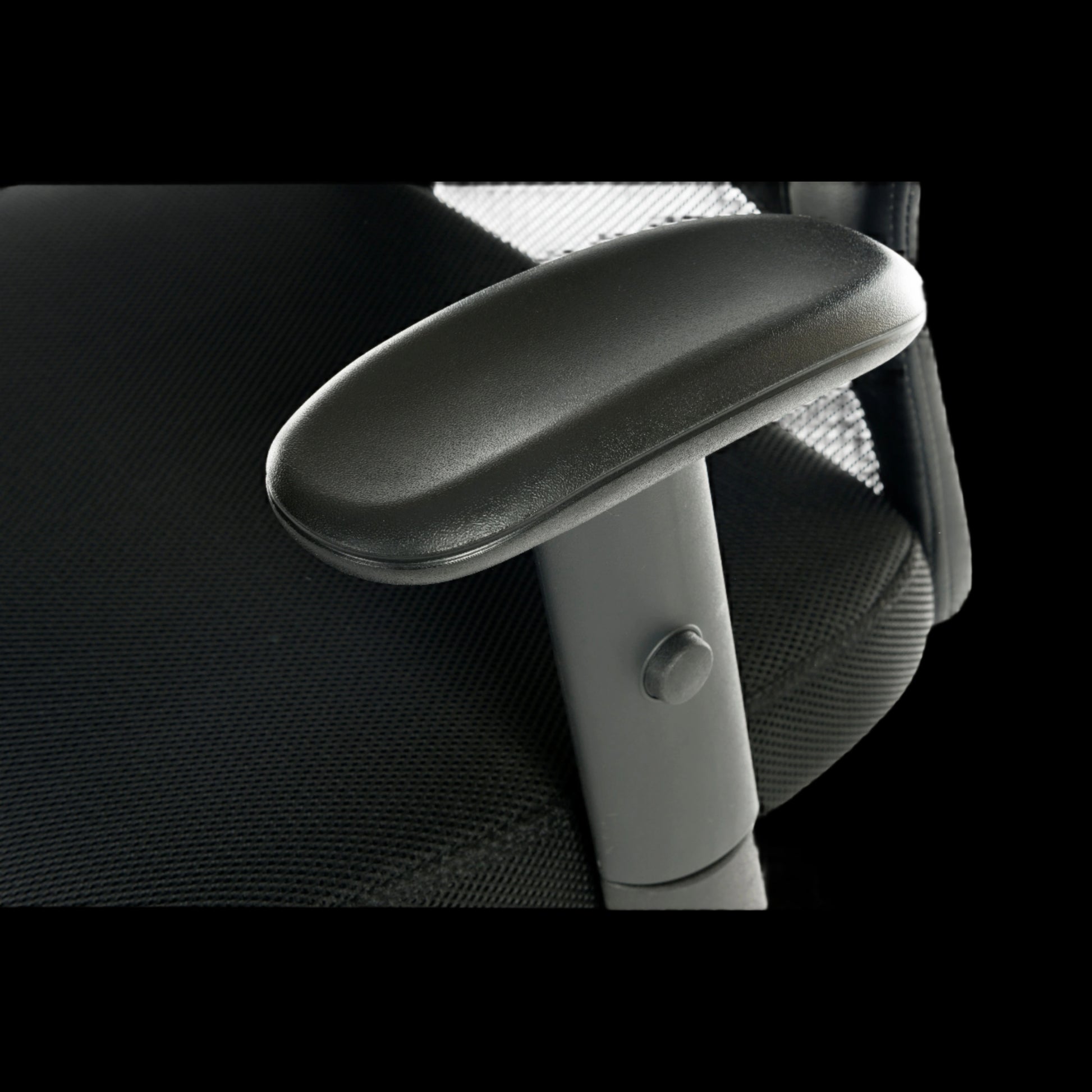 Close-up of a black office chair with armrest on a black background
