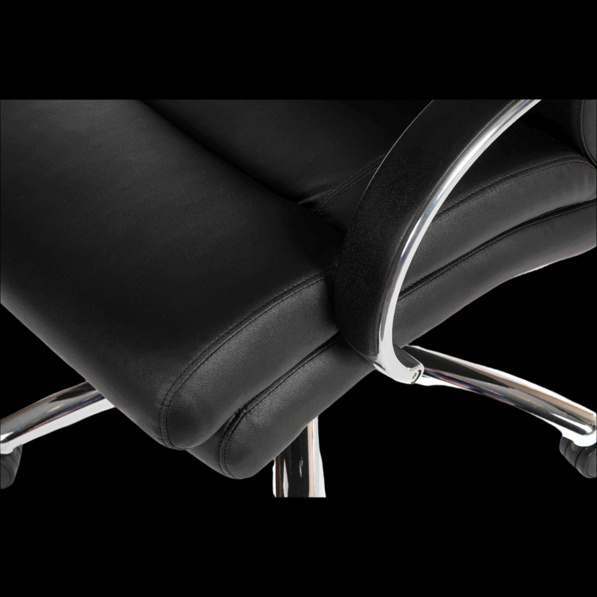 Close-up of a black office chair with chrome accents on a black background