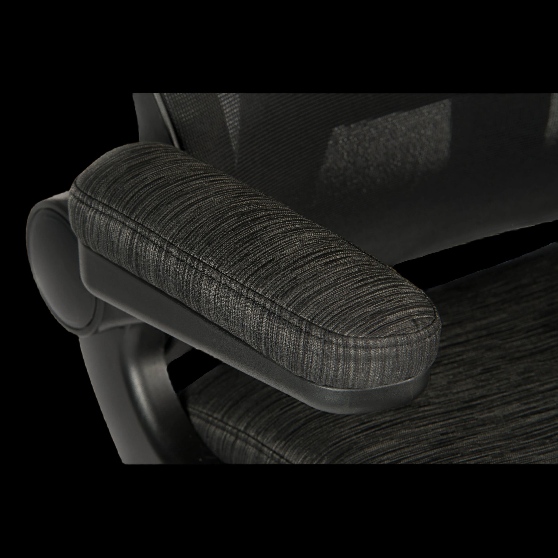 Close-up of a textured armrest on an office chair with a black background