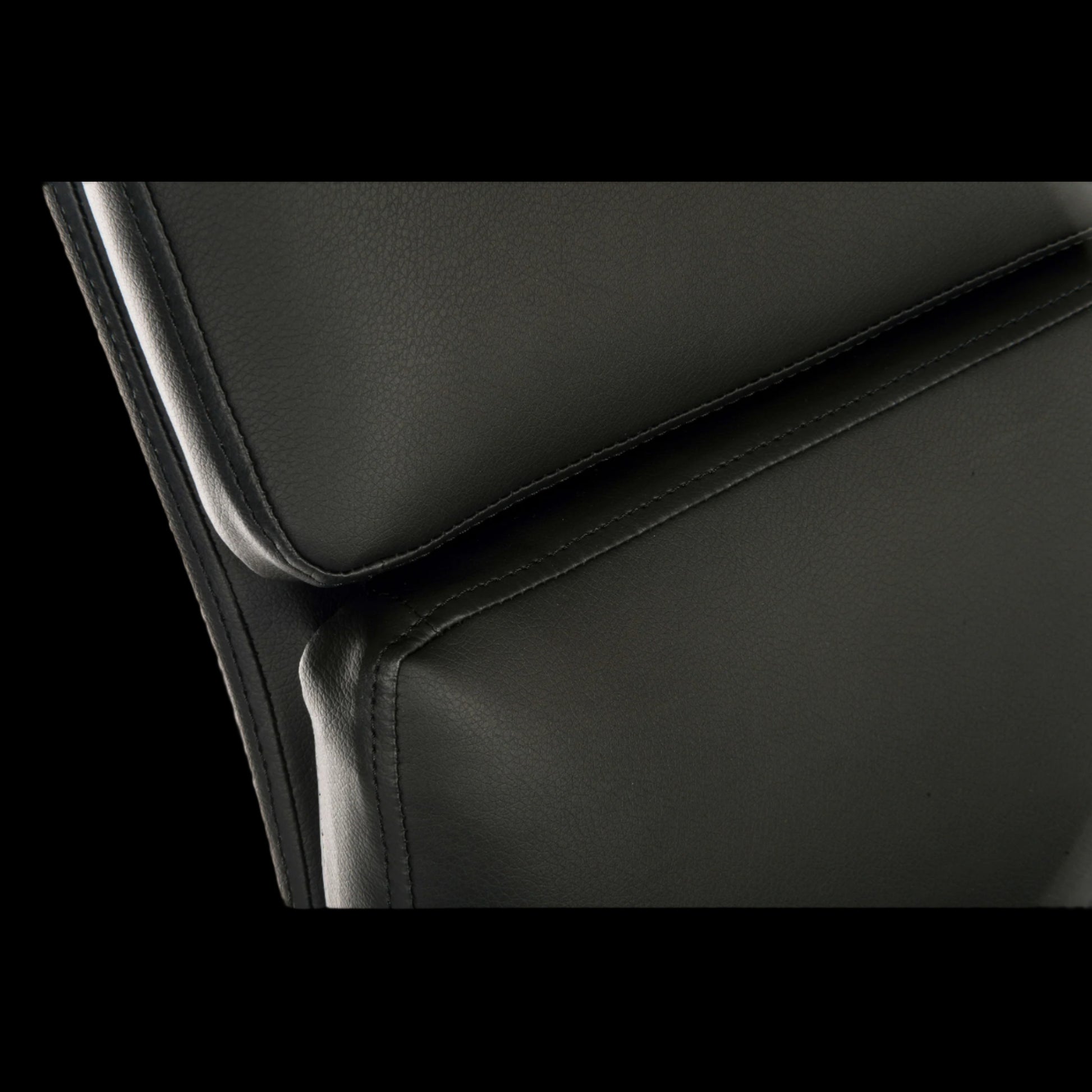 Close-up of a black leather chair with a focus on the seat and backrest.