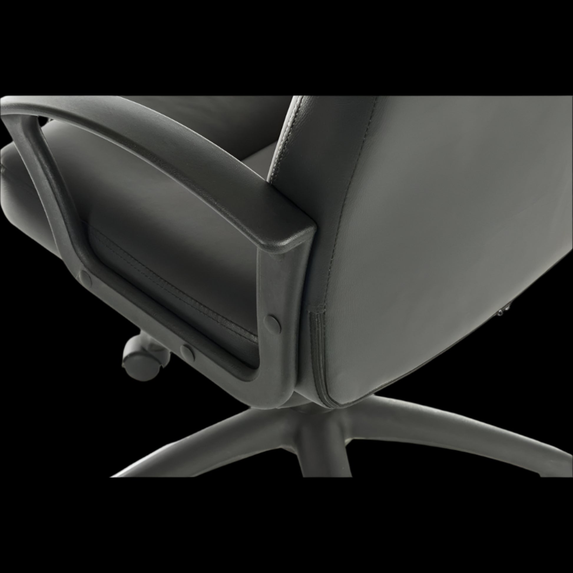 Close-up of a black office chair with a black background
