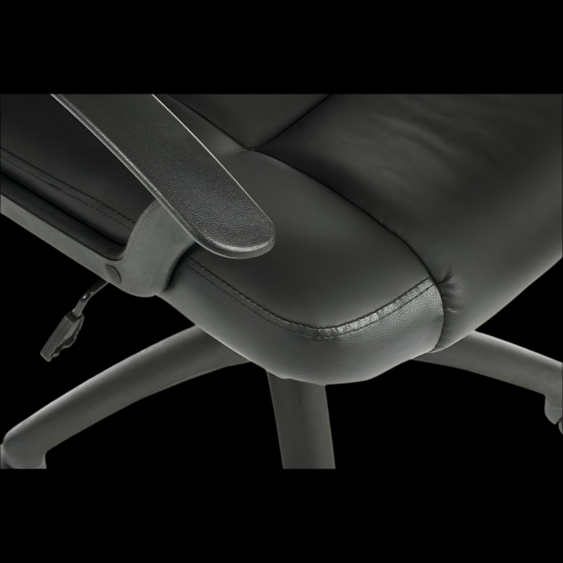 Close-up of a black office chair with armrests on a black background