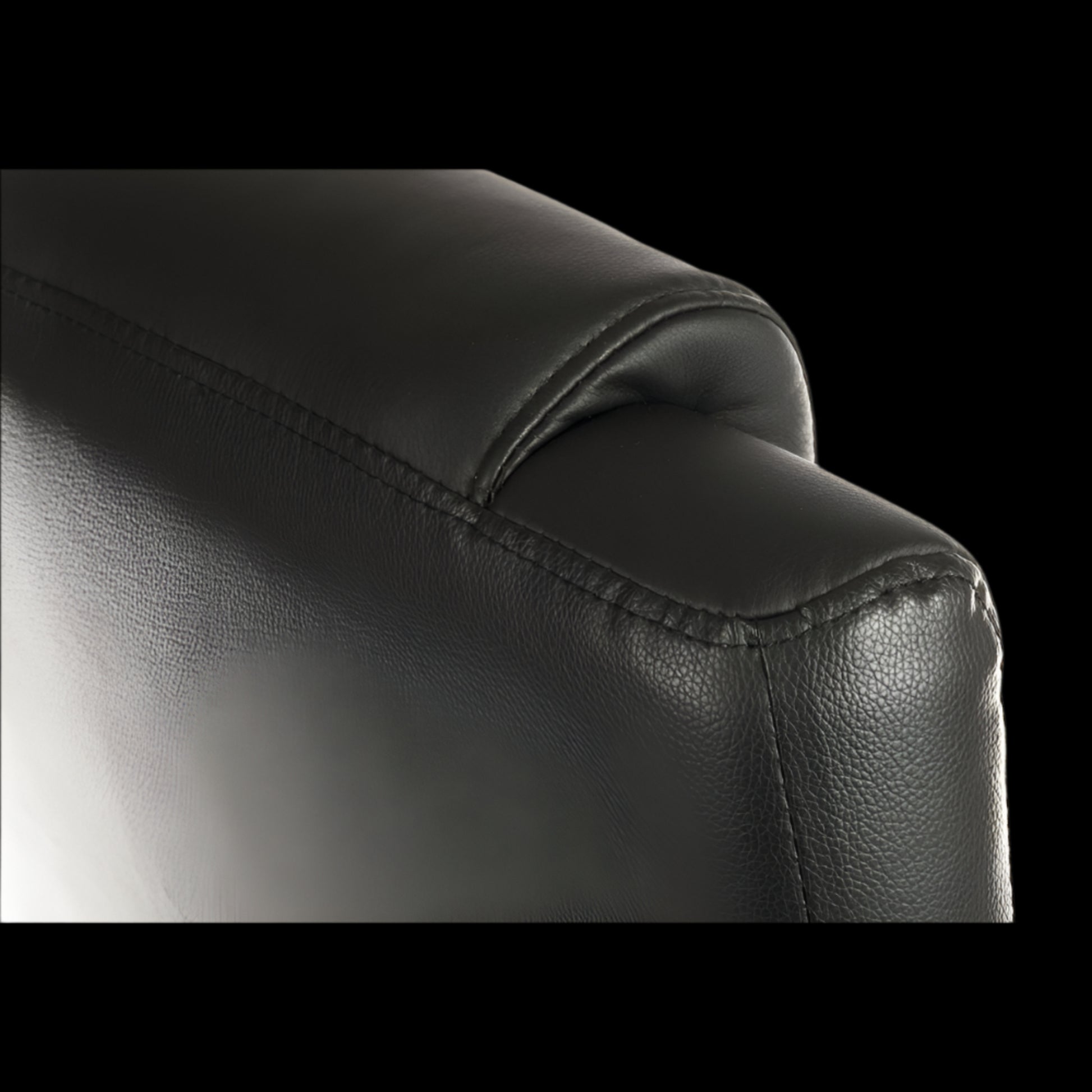 Close-up of a black leather armchair corner on a black background
