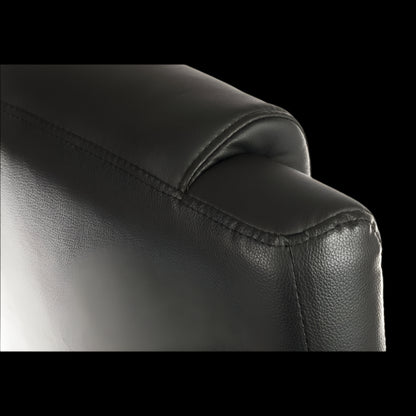 Close-up of a black leather armchair corner on a black background