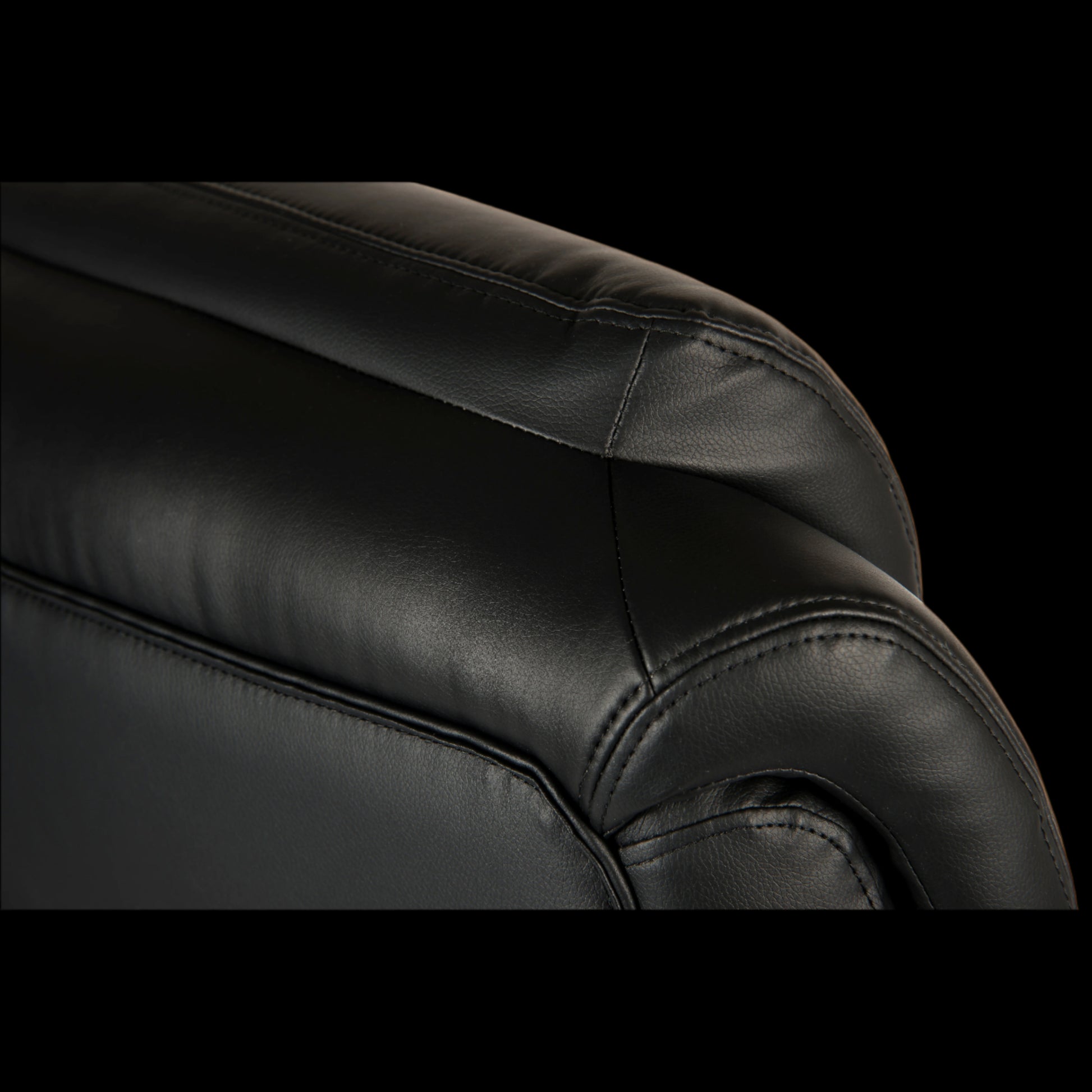 Close-up of a black leather armchair with visible stitching on a black background