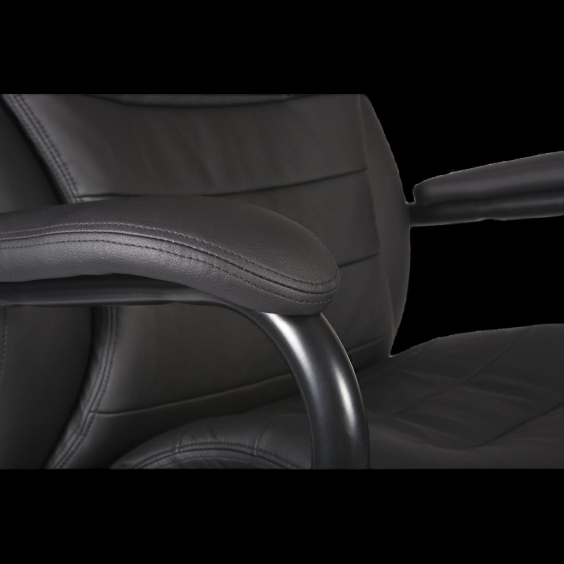 Close-up of a black office chair with armrests on a black background