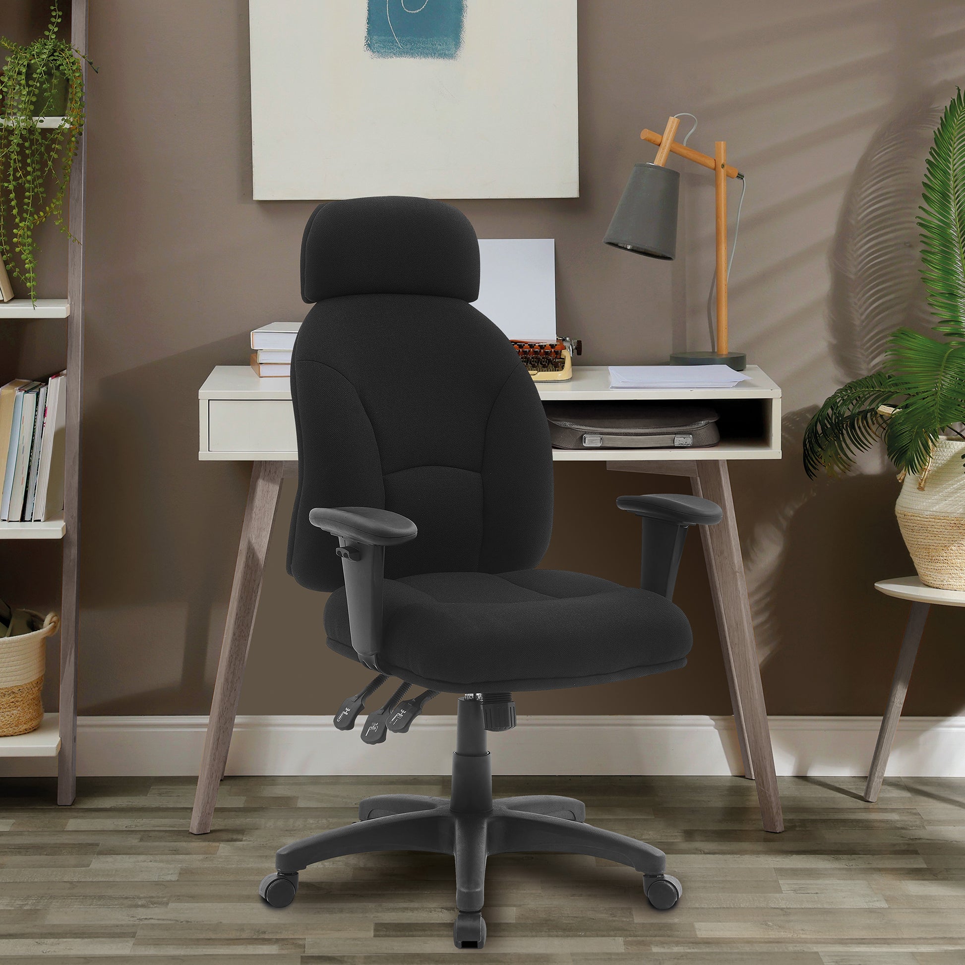 Black office chair in front of a white desk with a lamp and books in a room setting.