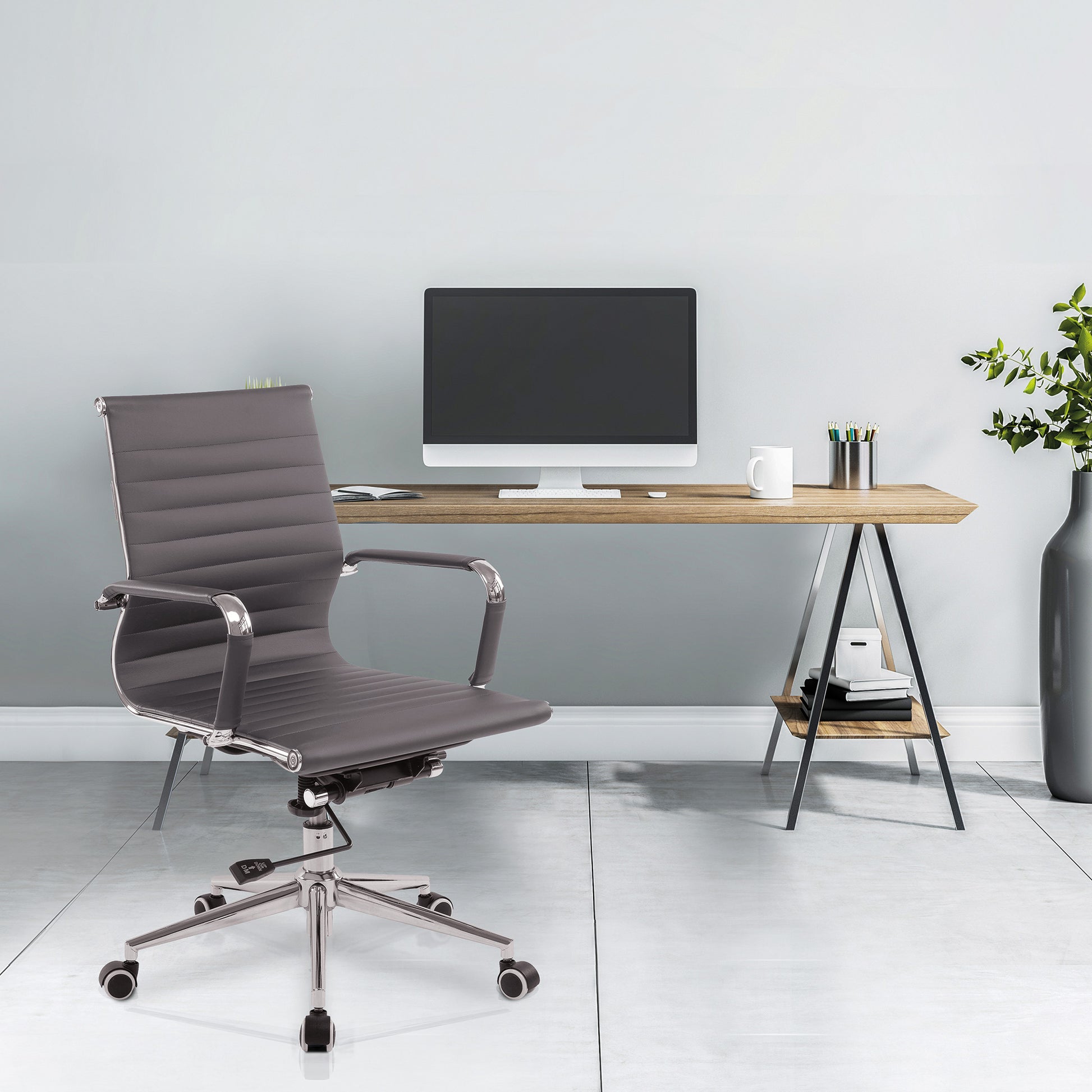 Modern office desk with a chair and computer setup against a light gray wall.