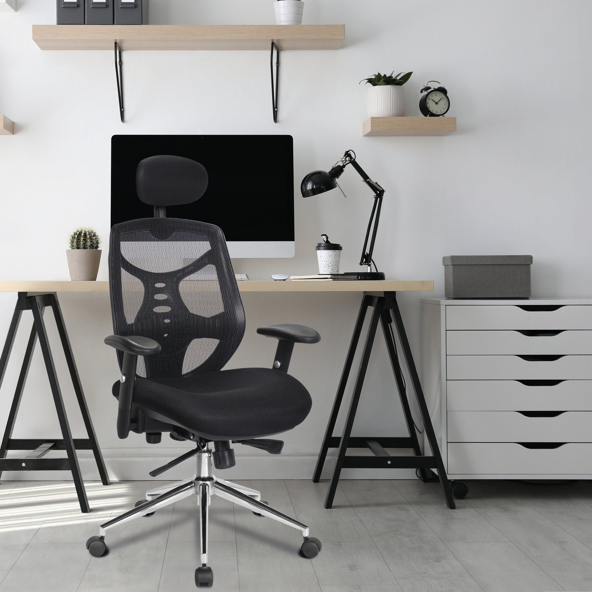 Modern office setup with a black ergonomic chair, desk, computer monitor, and white storage drawers.