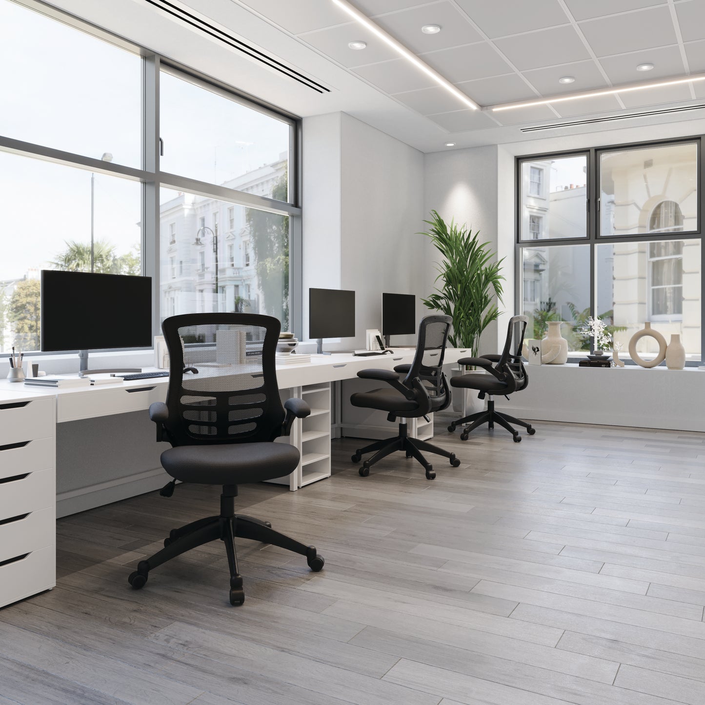 Modern office with desks, chairs, and large windows.