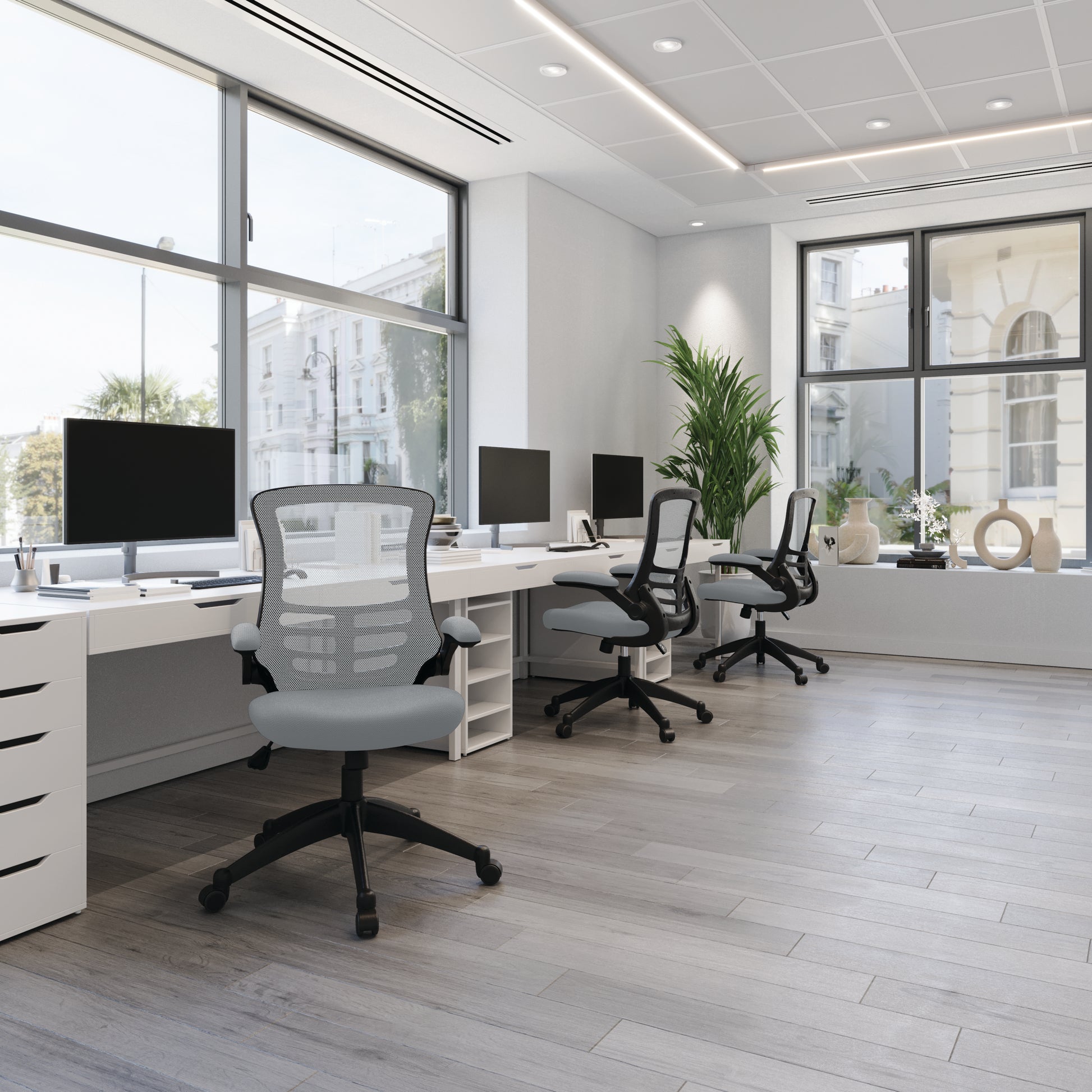 Modern office with desks, chairs, and large windows.