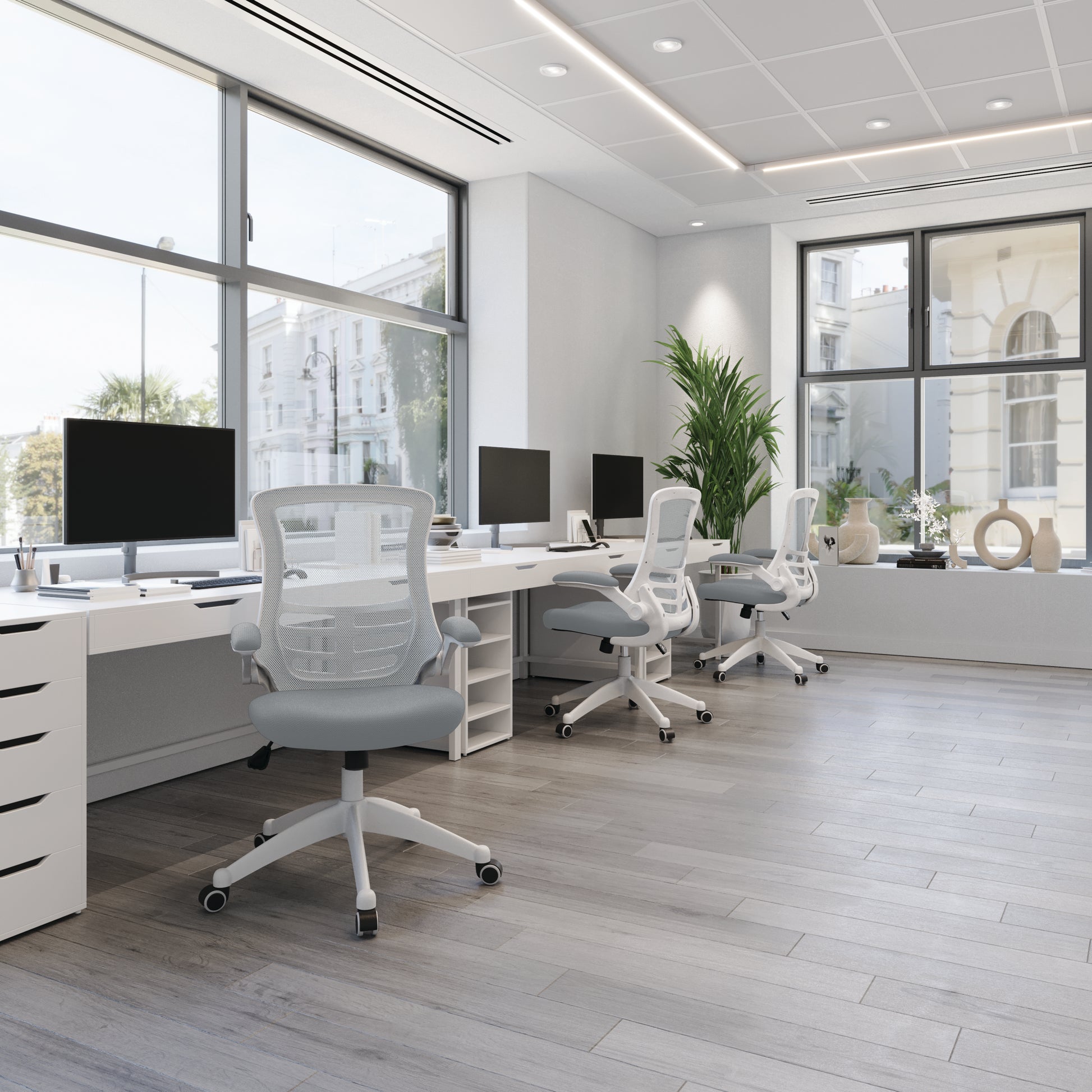 Modern office with white desks, chairs, and computer monitors.